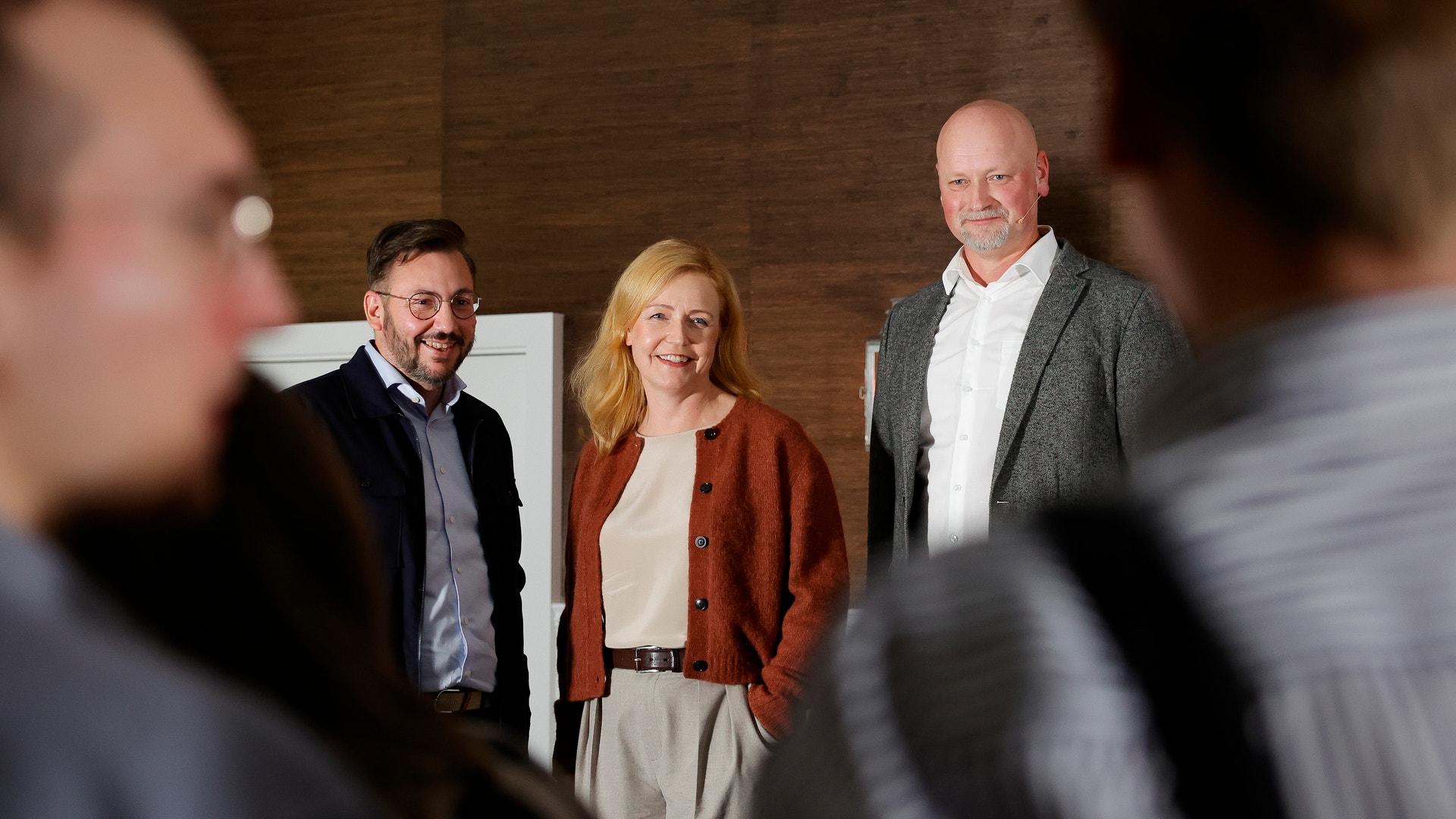 Tre personer i affärskläder står tillsammans på en gata framför gamla byggnader.