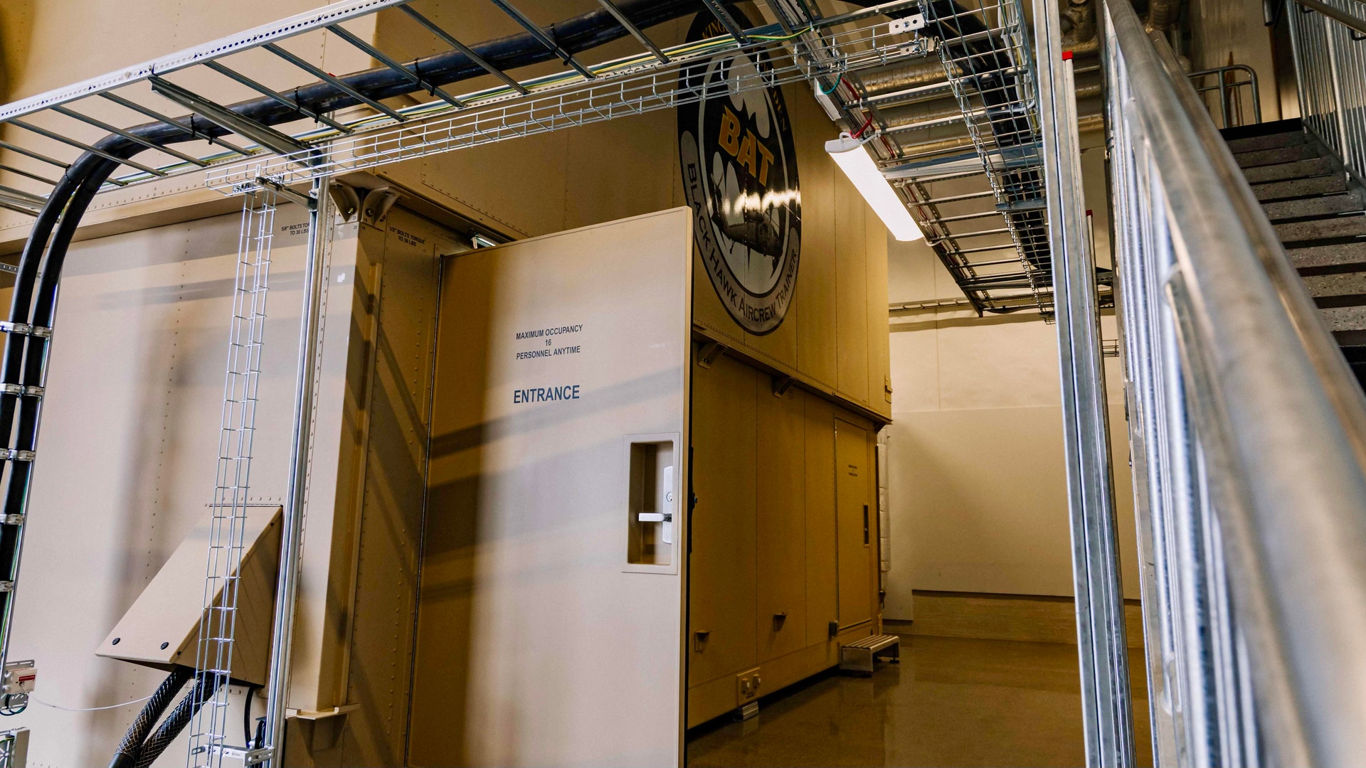 Stor gul industriell enhet eller testchamber med metallkonstruktion och ingångsöppning i ett laboratorium eller industrianläggning.