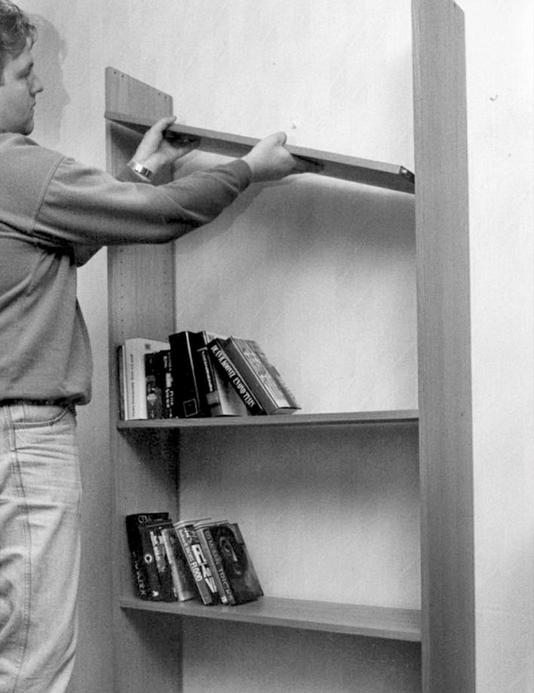 En person monterar en hylla på en vägg.