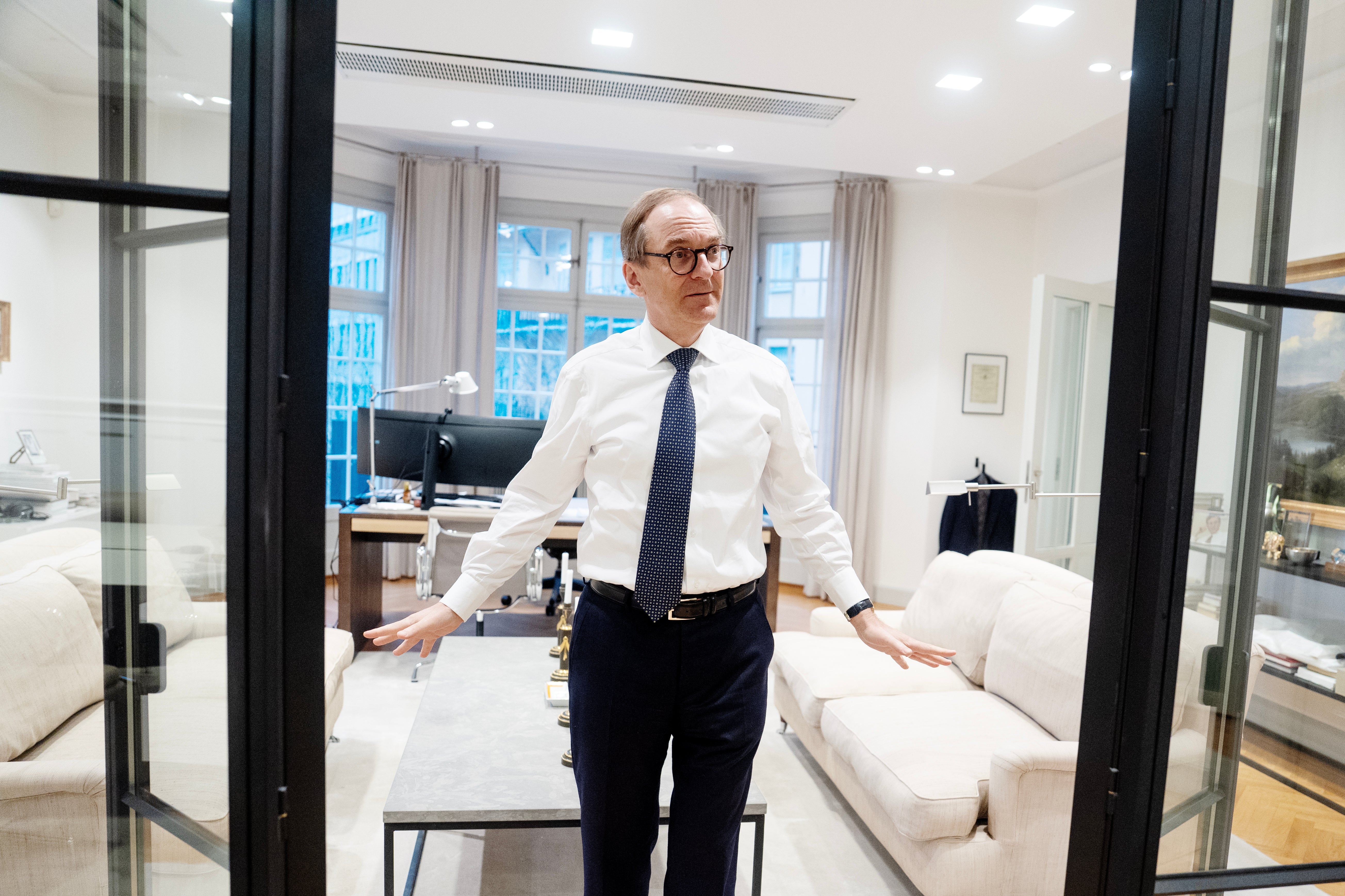 Porträtt av en man i vit skjorta och slips som står i ett modernt kontor.