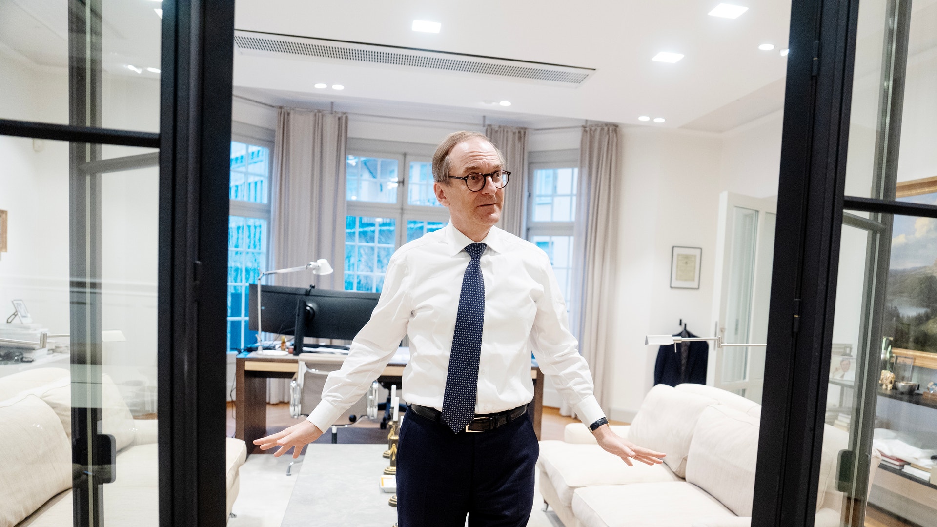 Porträtt av en man i vit skjorta och slips som står i ett modernt kontor.