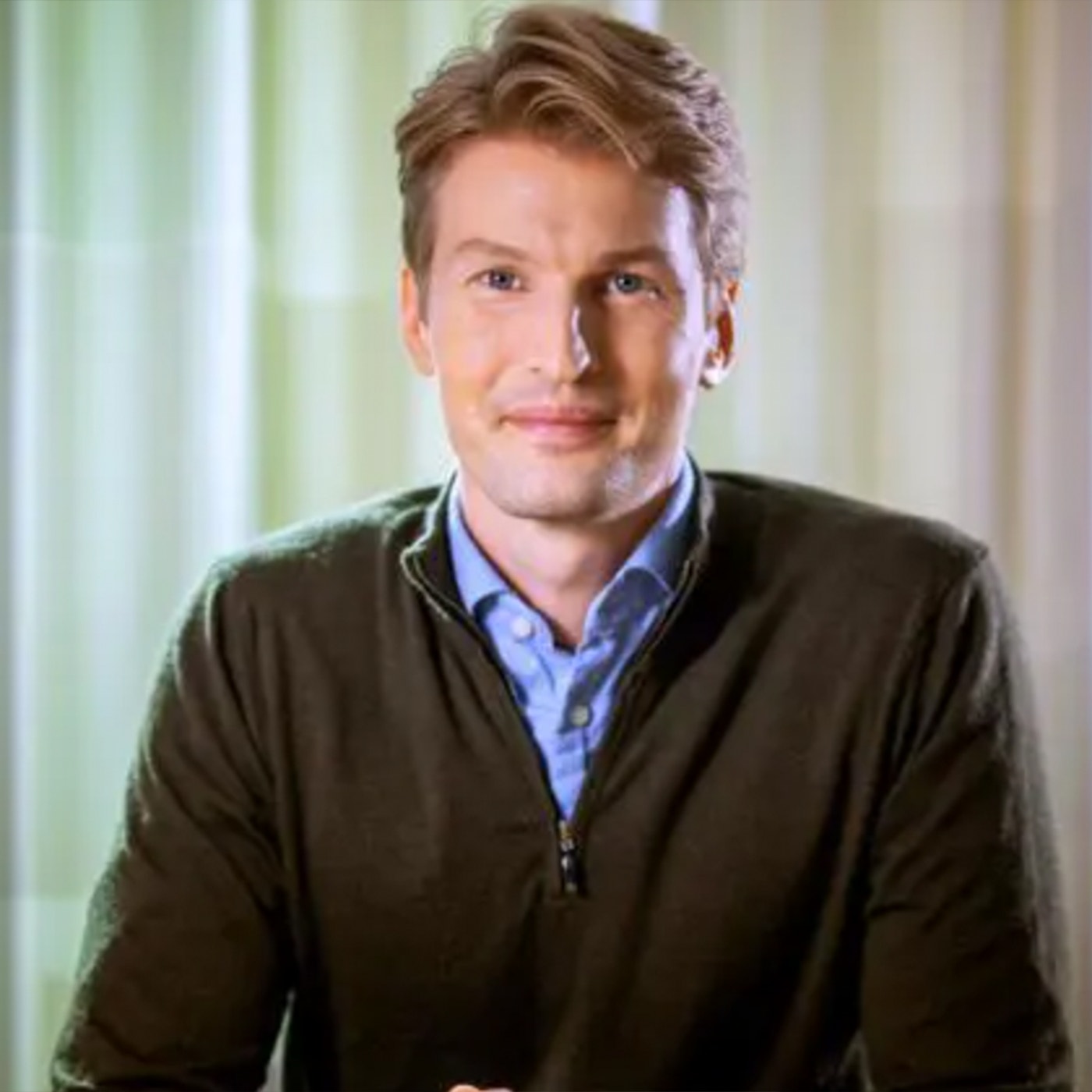 Pressbild på Gustaf Linnell, räntechef på Storebrand Sverige. Han sitter i skjorta och pullover.