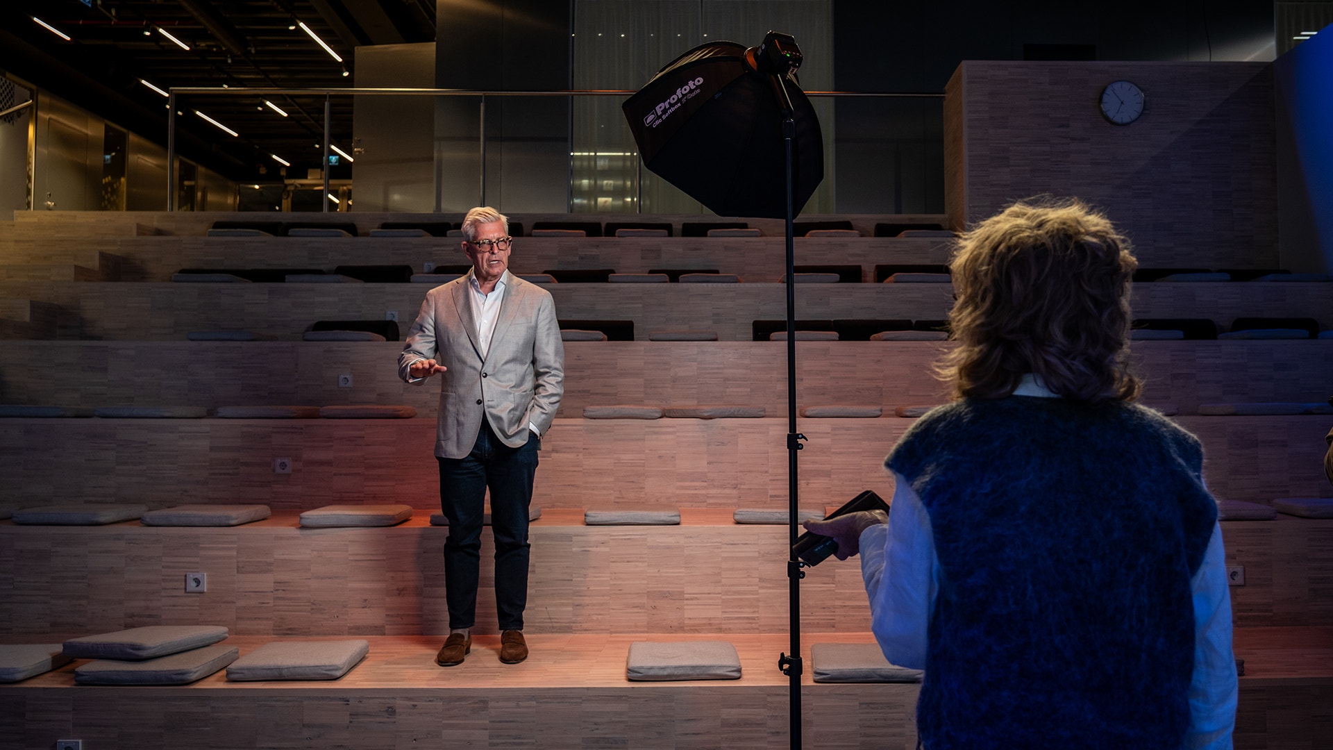 En man i ljus kavaj och en kvinna i blå jacka under en studiofotografering med professionell belysningsutrustning.