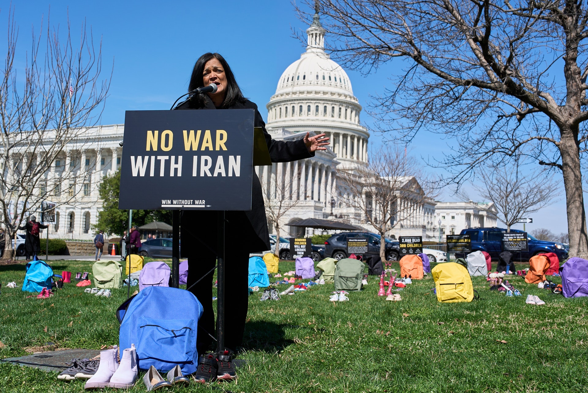 Person håller upp en skylt med texten "NO WAR WITH IRAN" framför USA:s Kapitolium under en fredlig protest.