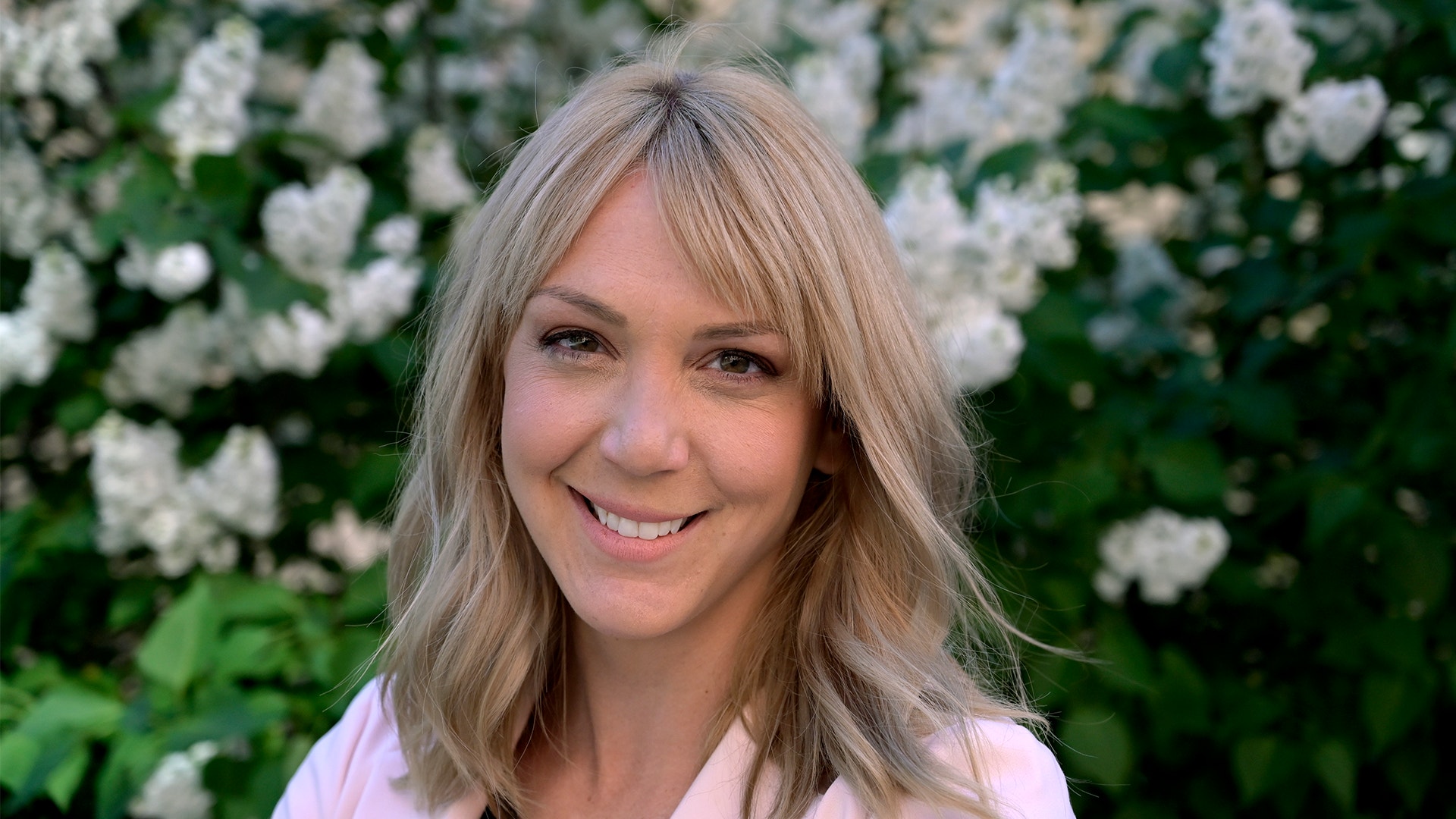 Frida Bratt framför en grönskande buske.