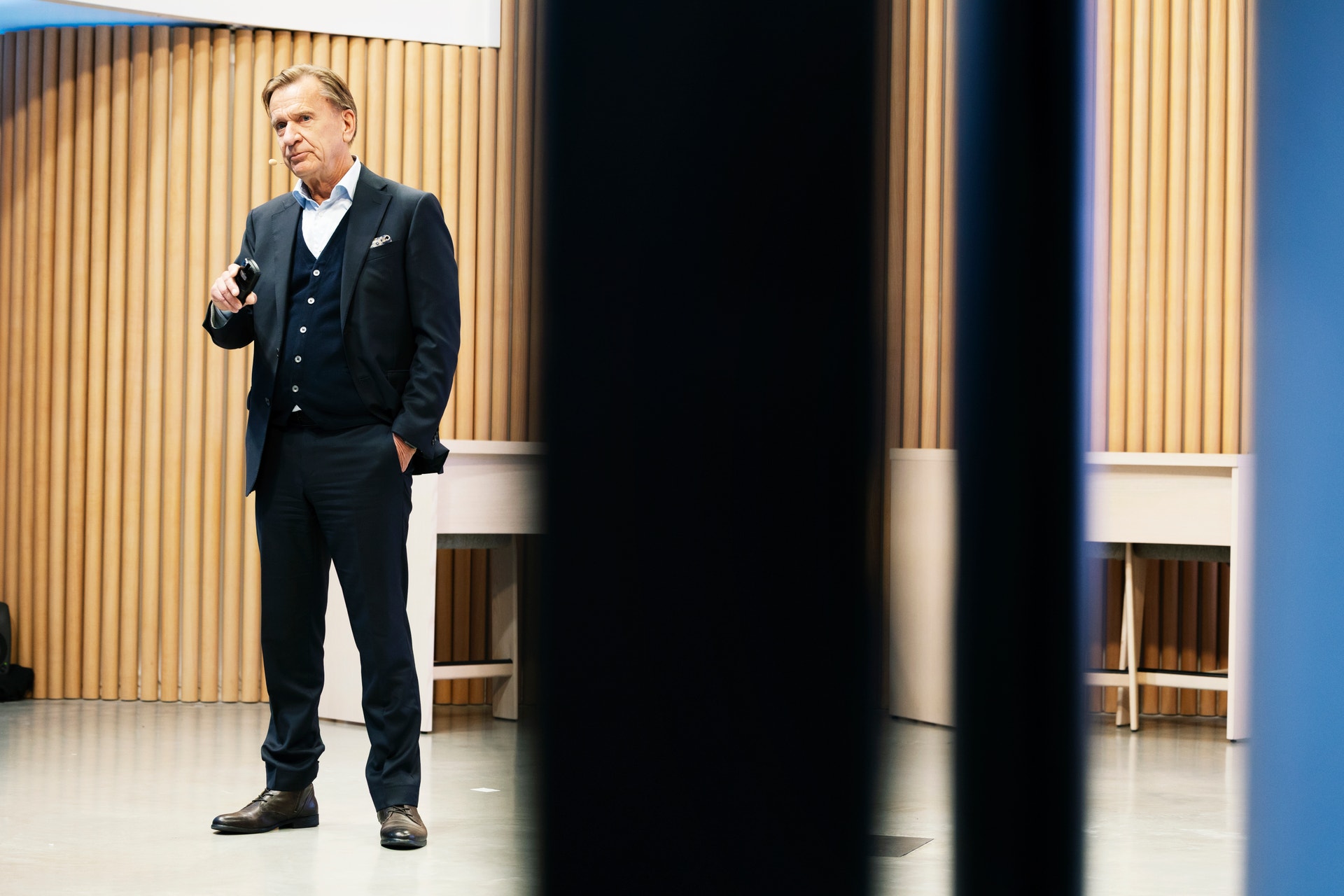 En man i kostym håller en presentation och talar till en publik.