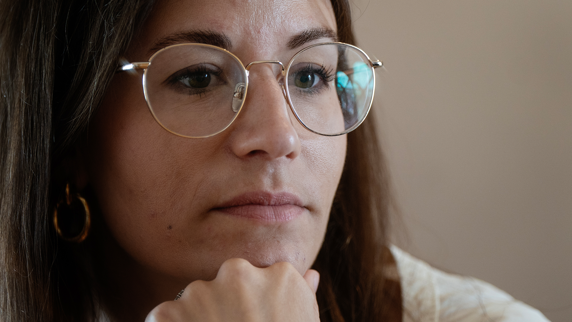 Hanna Andreen sitter vid ett bord med guldiga smycken och guldiga bågar på glasögonen. 