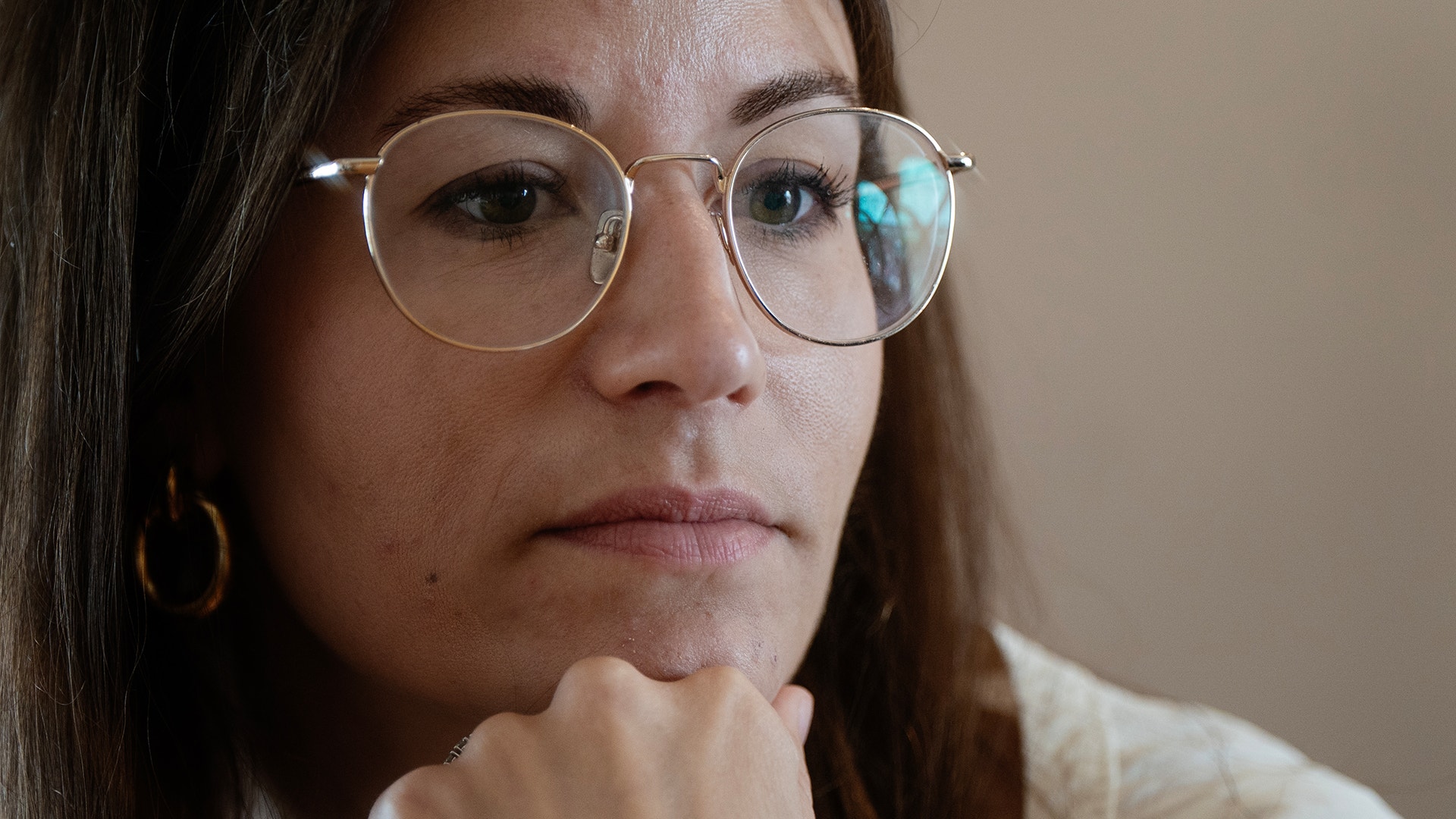 Hanna Andreen sitter vid ett bord med guldiga smycken och guldiga bågar på glasögonen. 