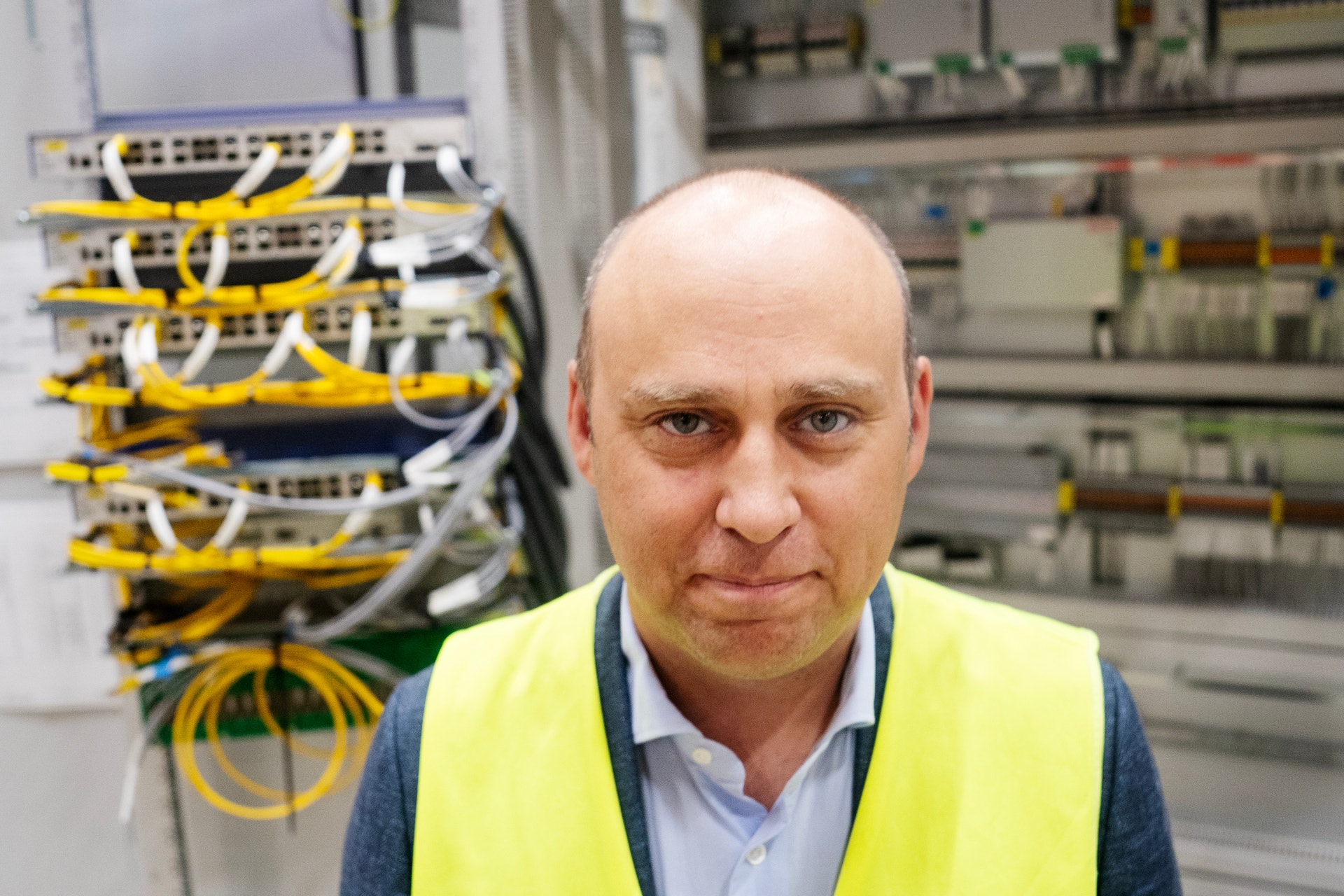 Man i gul säkerhetväst framför serverutrustning och nätverkskablar