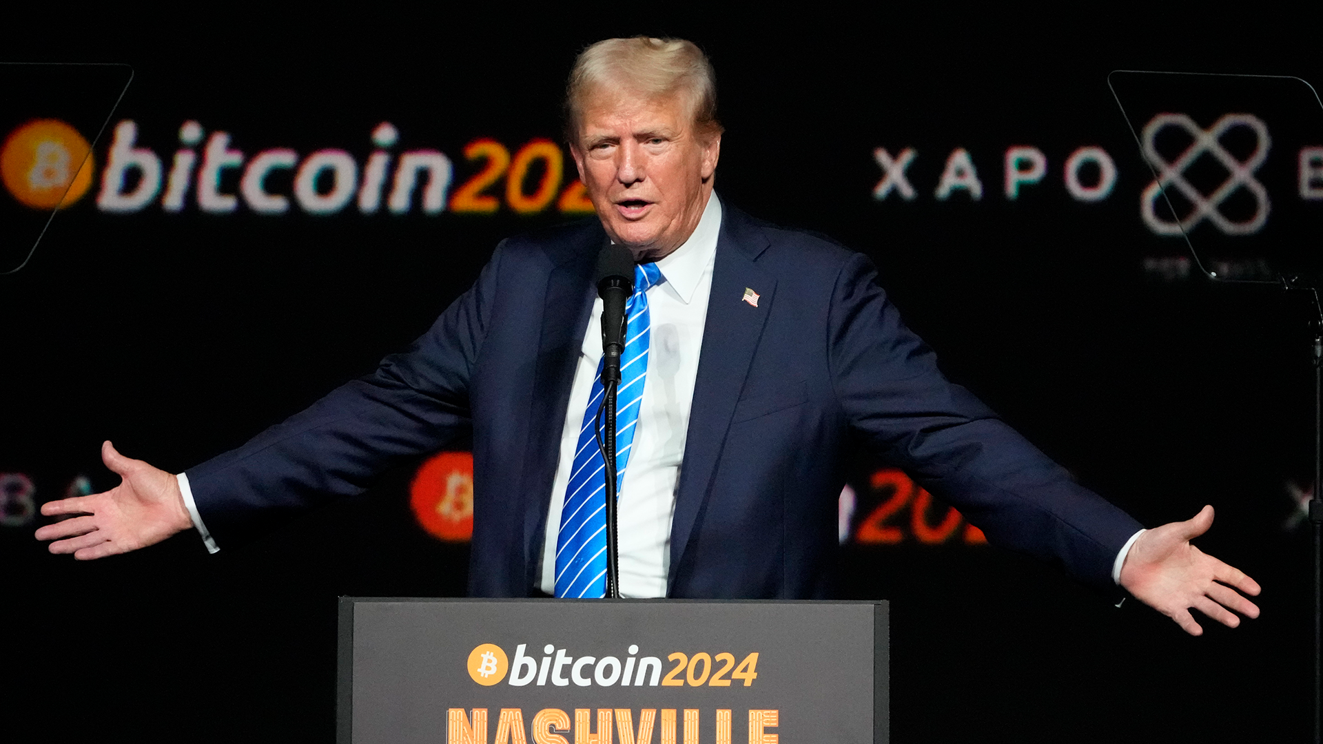Donald Trump talar på Bitcoin 2024-konferensen. Han sträcker ut händerna och ser nöjd ut.