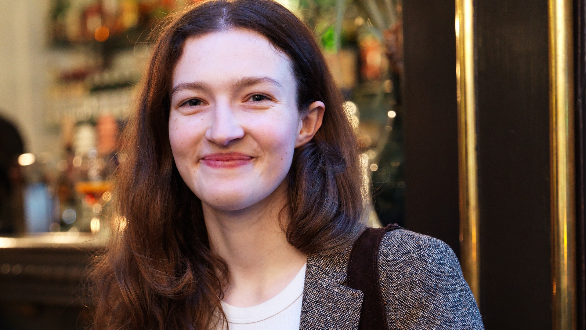 Porträtt av en ung kvinna med långt mörkt hår som ler mot kameran