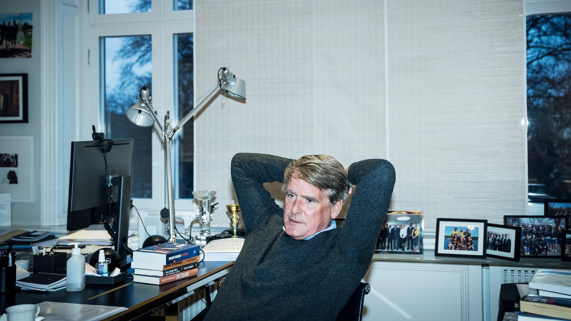 Man sitter avslappnad vid sitt skrivbord i ett modernt kontor, lutar sig bakåt i stolen med händerna bakom huvudet.