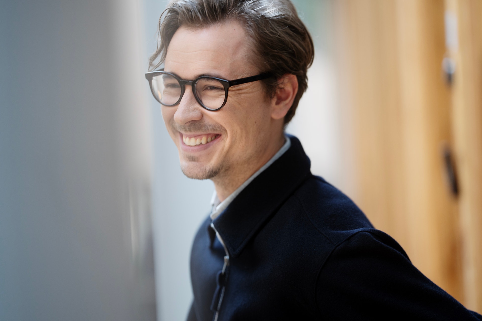 Porträtt av en man med glasögon som ler mot kameran