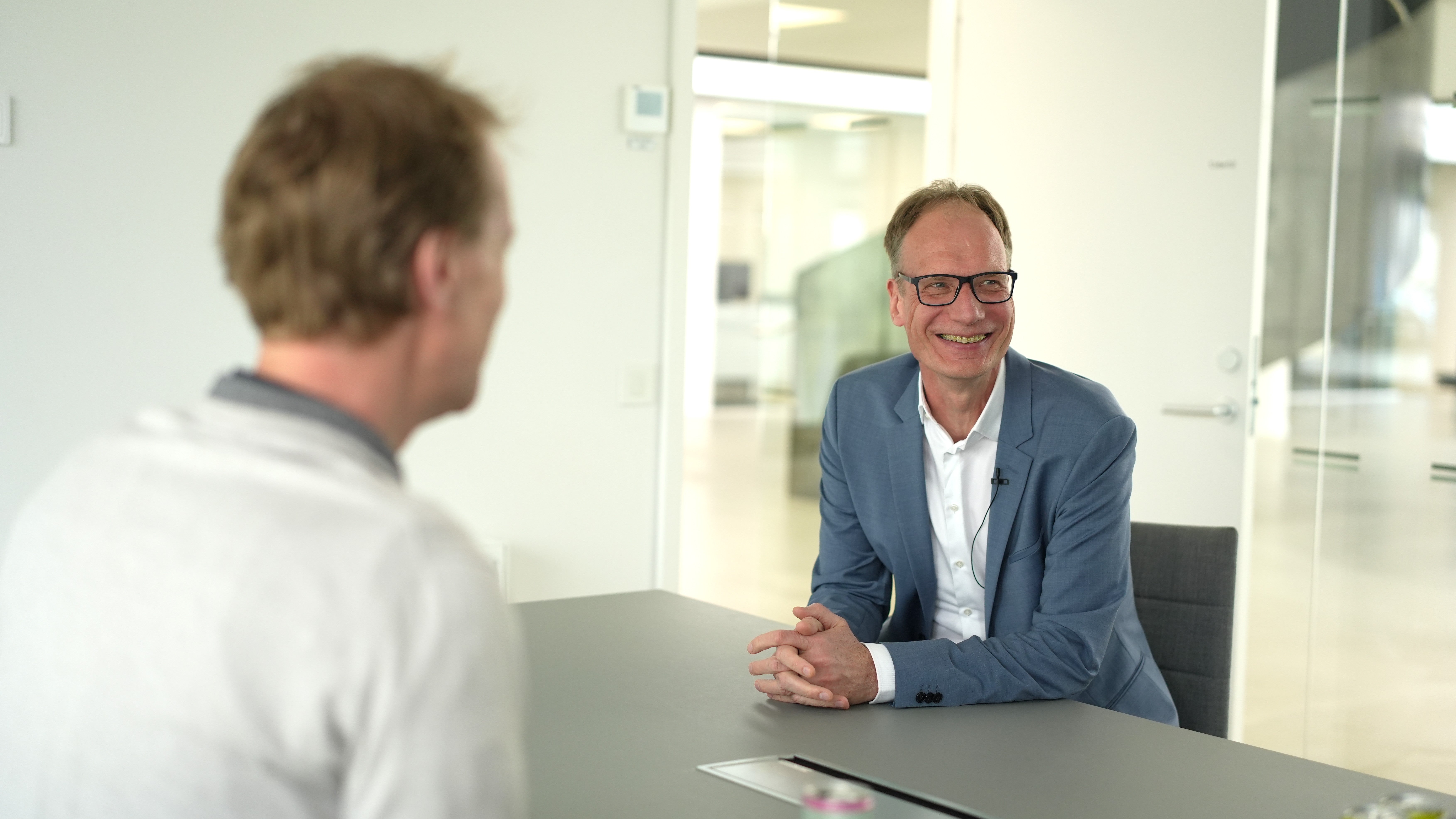 Två män i samtal vid ett bord i ett modernt kontor.