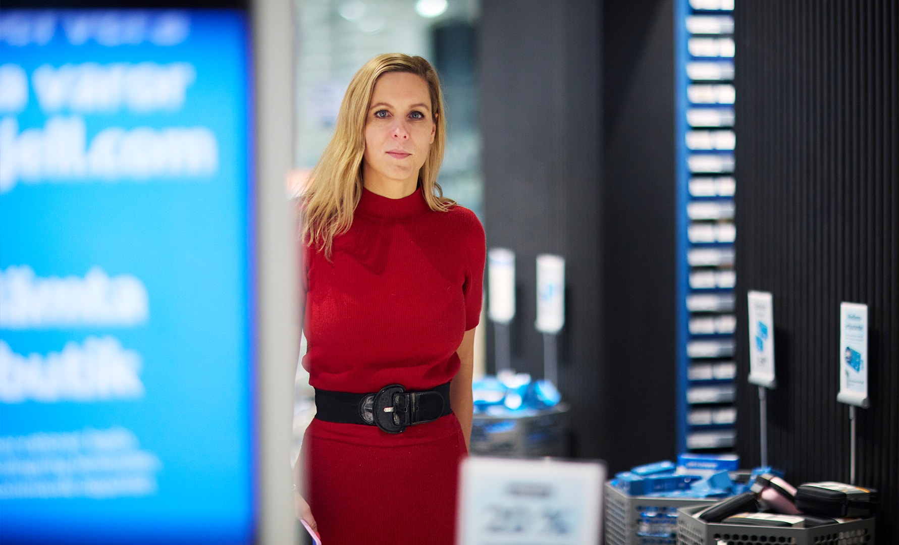Porträtt av en kvinna i röd tröja i en modern kontorsmiljö med blå belysning