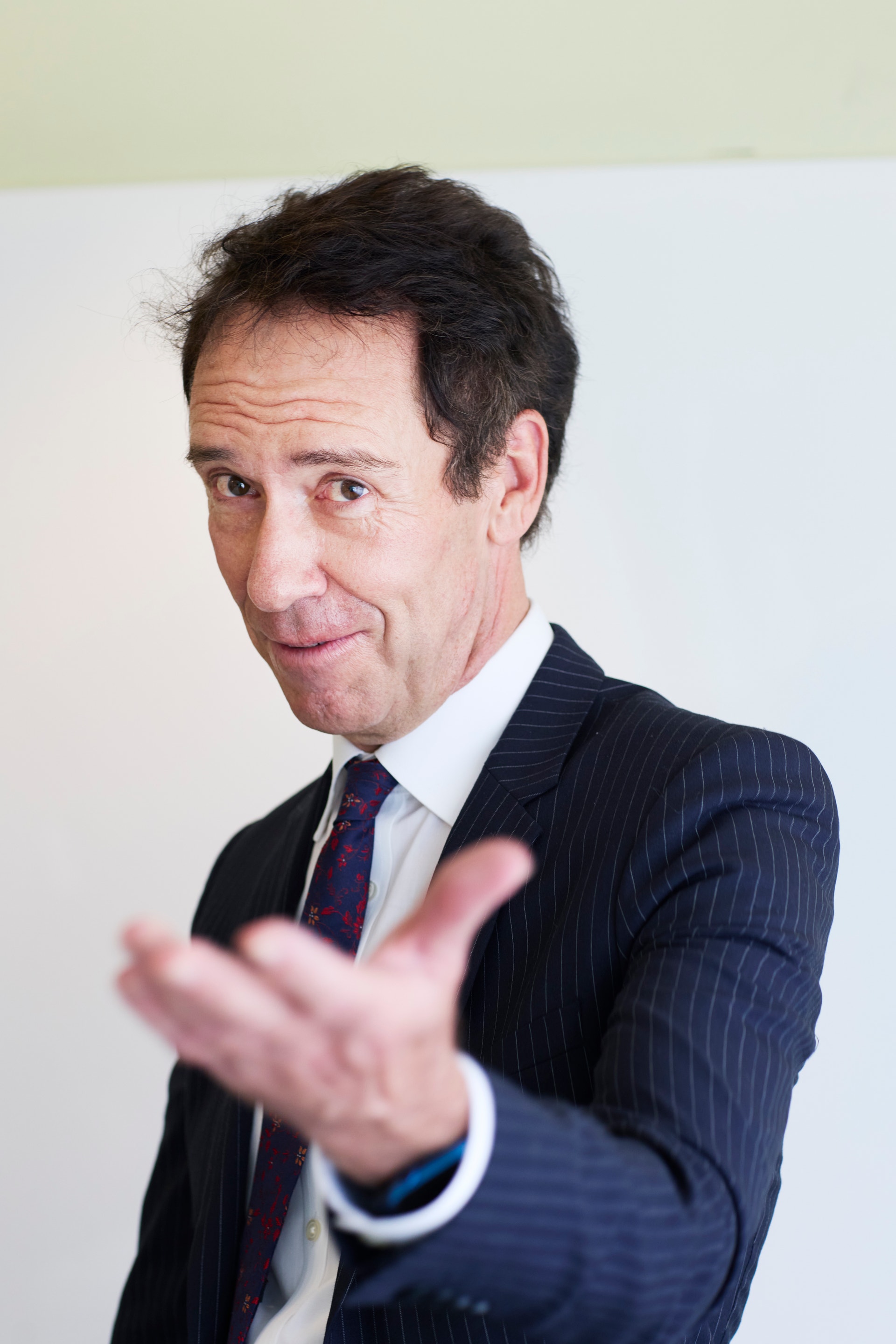 Byron Sharp, tittar in i kameran och räcker fram handen mot kameran.