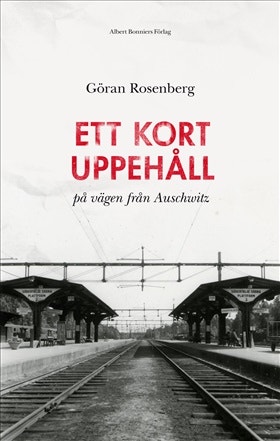 Bokomslag för 'Ett kort uppehål - på vägen från Auschwitz' av Göran Rosenberg. Bilden visar järnvägsspår på en station med överbyggnader, i svart och vitt.