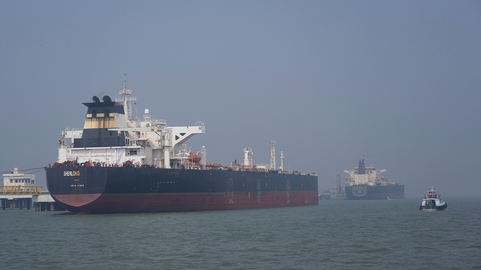 Stora oljetankfartyg ankrade i hamn med industriell infrastruktur i bakgrunden