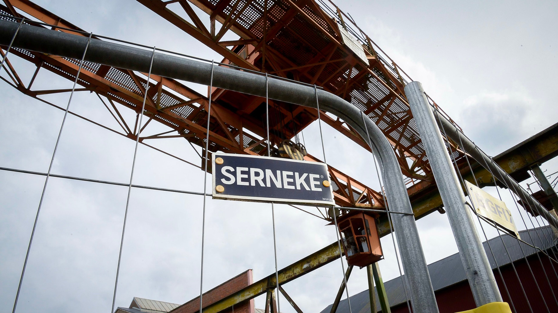 Industriell stålkonstruktion med Serneke-skylt och stora glasfönster under molnig himmel.