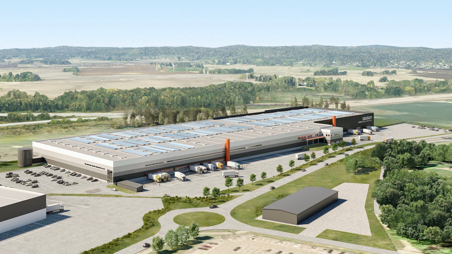 Flygfoto över Slättö Vätet Stadium, en modern sportanläggning med solpaneler på taket, omgiven av gröna fält och skogar.