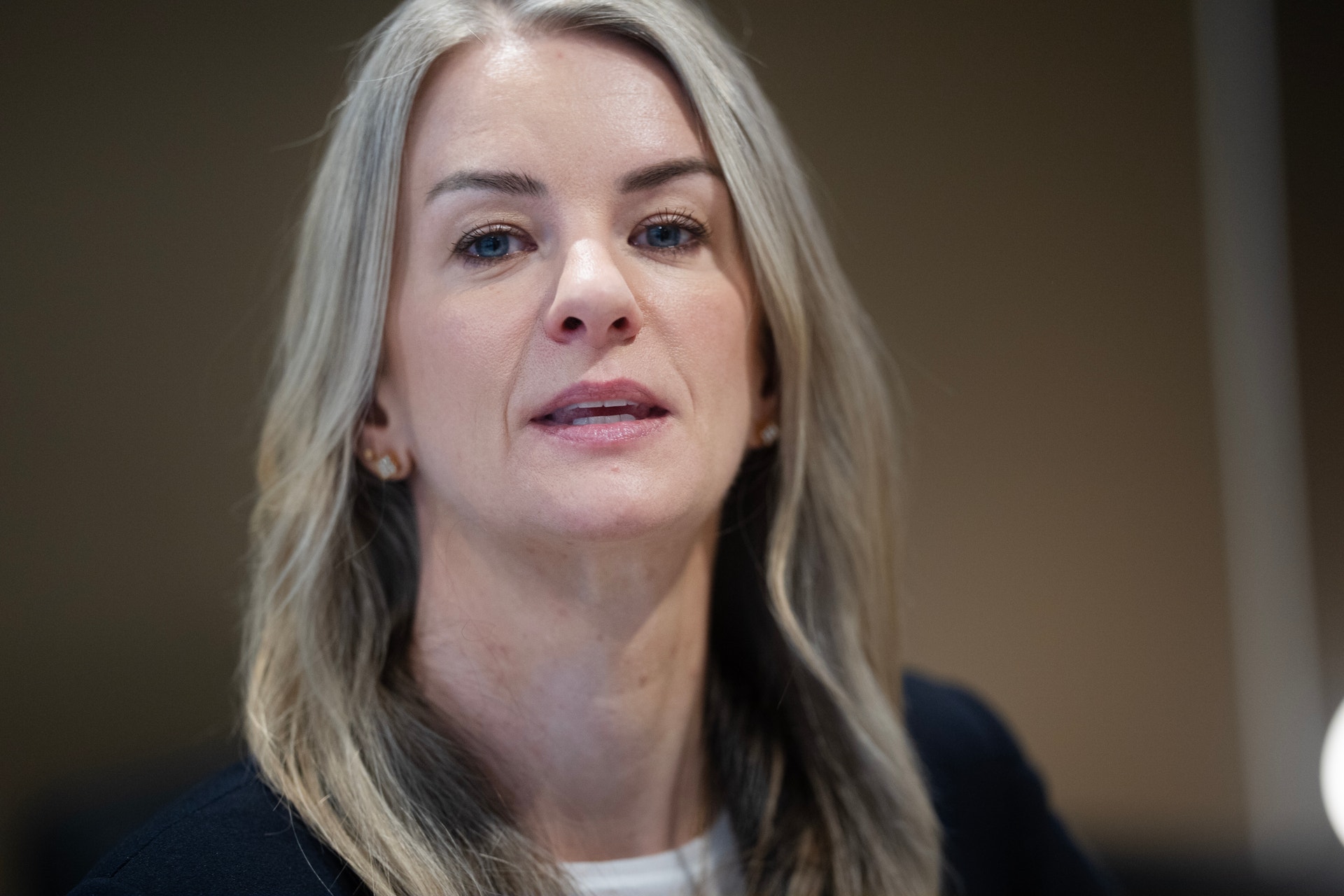 Porträtt av en kvinna med långt blont hår mot neutral bakgrund