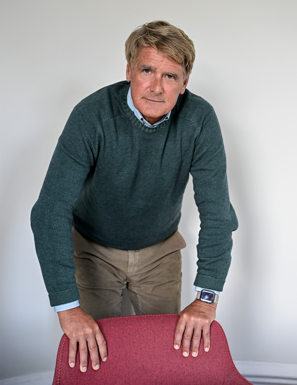 Finansmannen Christer Gardell varnar för riskerna med private credit och pekar på låg transparens. Han står bestämd vid en stol och har händerna på stolsryggen.