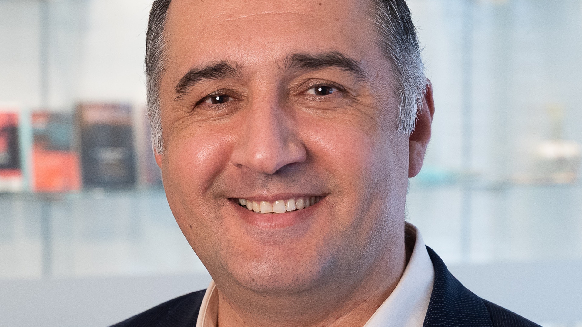 Porträttfoto av en man i mörk kostym mot en ljus bakgrund