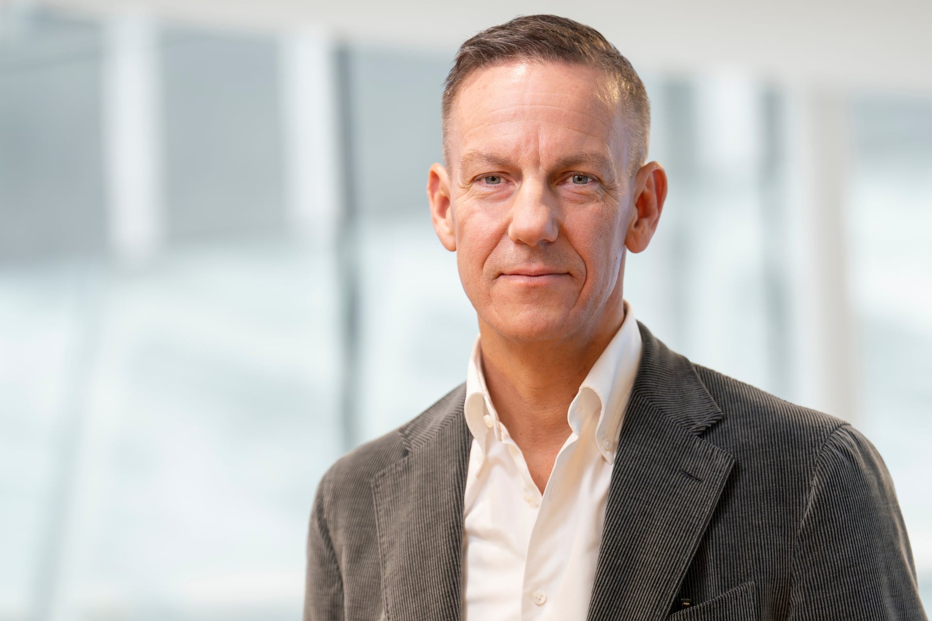 Porträtt av en man i affärskläder framför ett modernt kontorsinteriör
