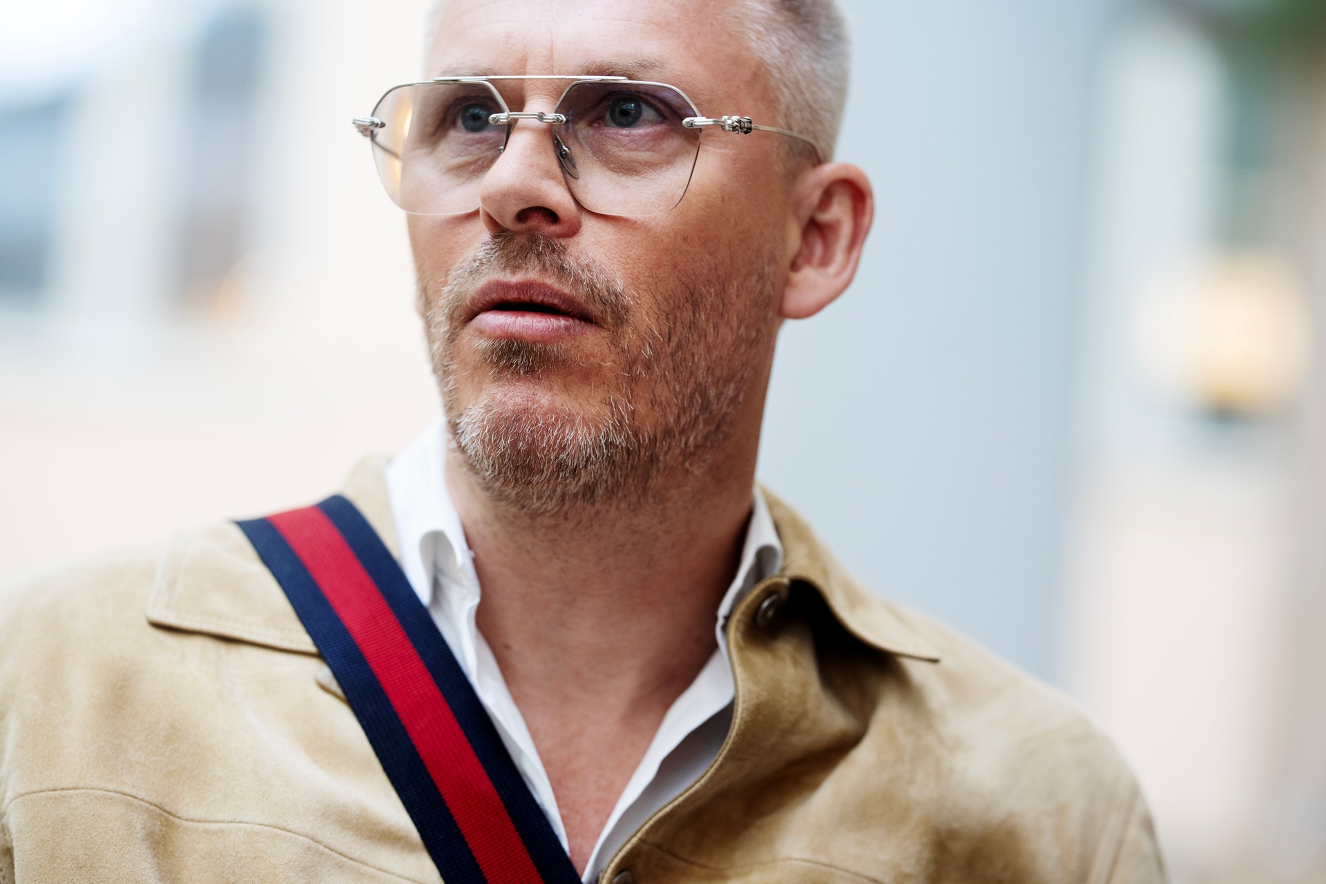 Porträtt av en man med glasögon och beige jacka