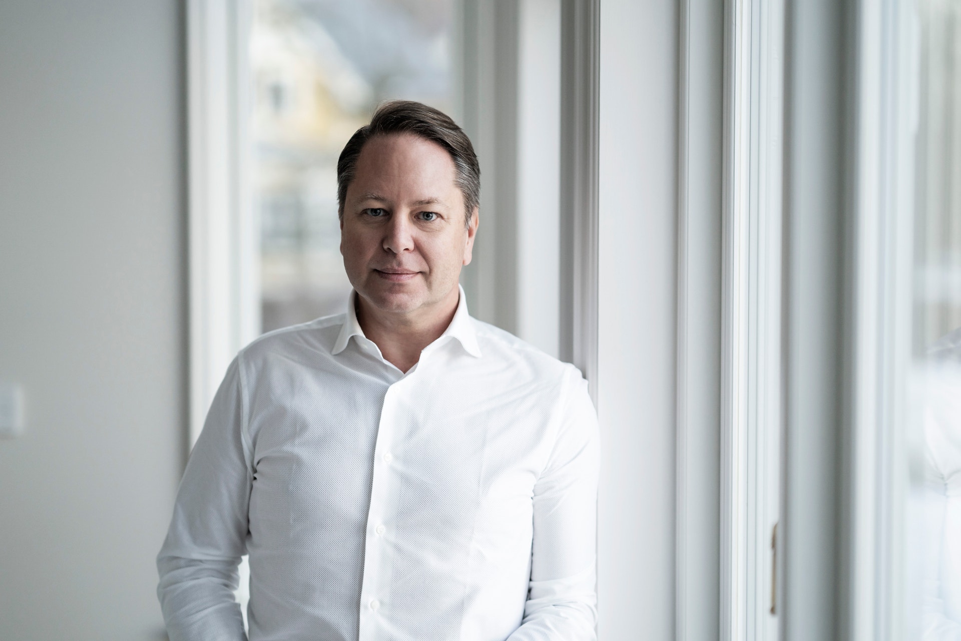 Porträtt av en man i vit skjorta som står framför ett fönster