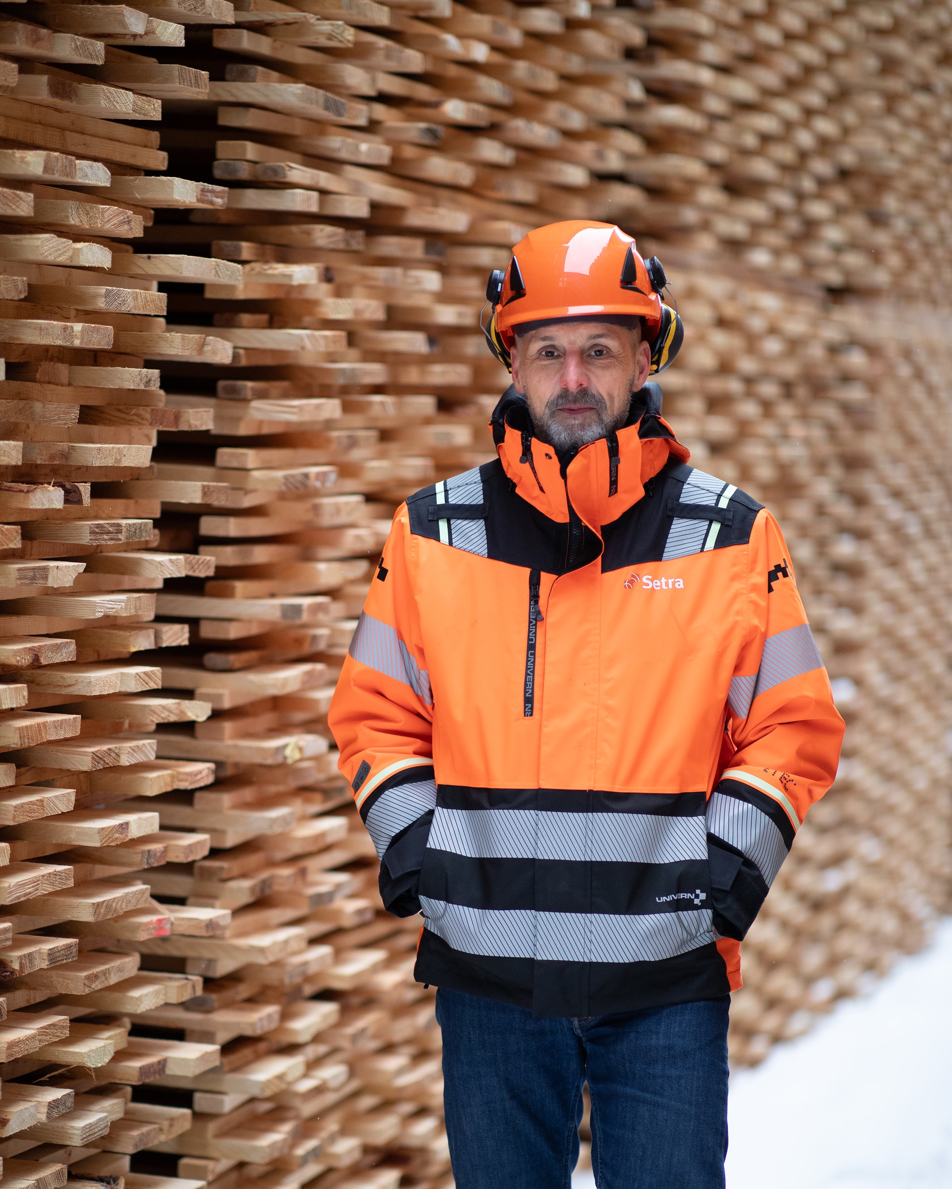 Arbetare i orange säkerhetskläder och hjälm framför en tegelvägg