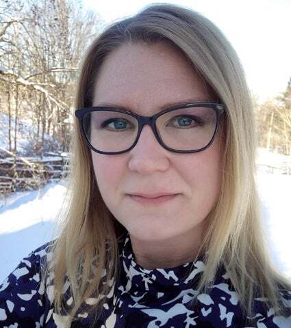 Porträtt av en kvinna med glasögon och blont hår, fotograferad utomhus i ett snölandskap.