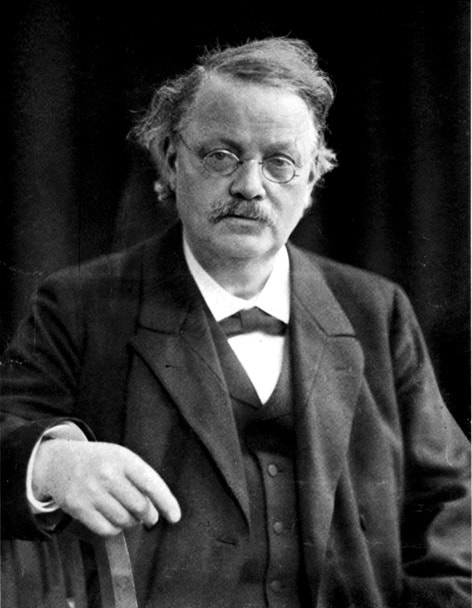 Svartvitt porträtt av en äldre man med glasögon och mustasch, iklädd formell kostym från början av 1900-talet.