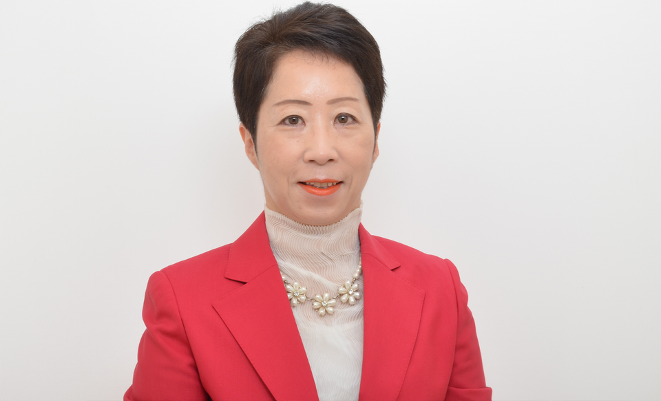 Porträttfoto av en kvinna i röd kavaj mot vit bakgrund