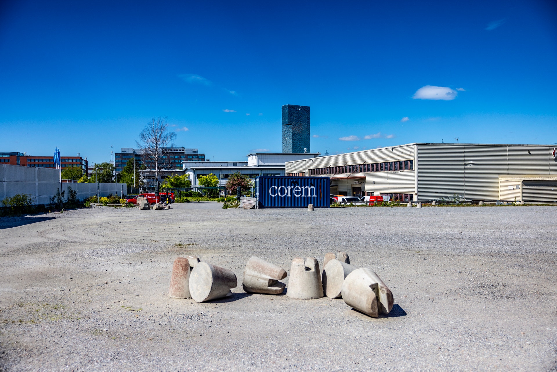 Industriområde i Kista med betongrör på marken och moderna byggnader i bakgrunden under blå himmel.
