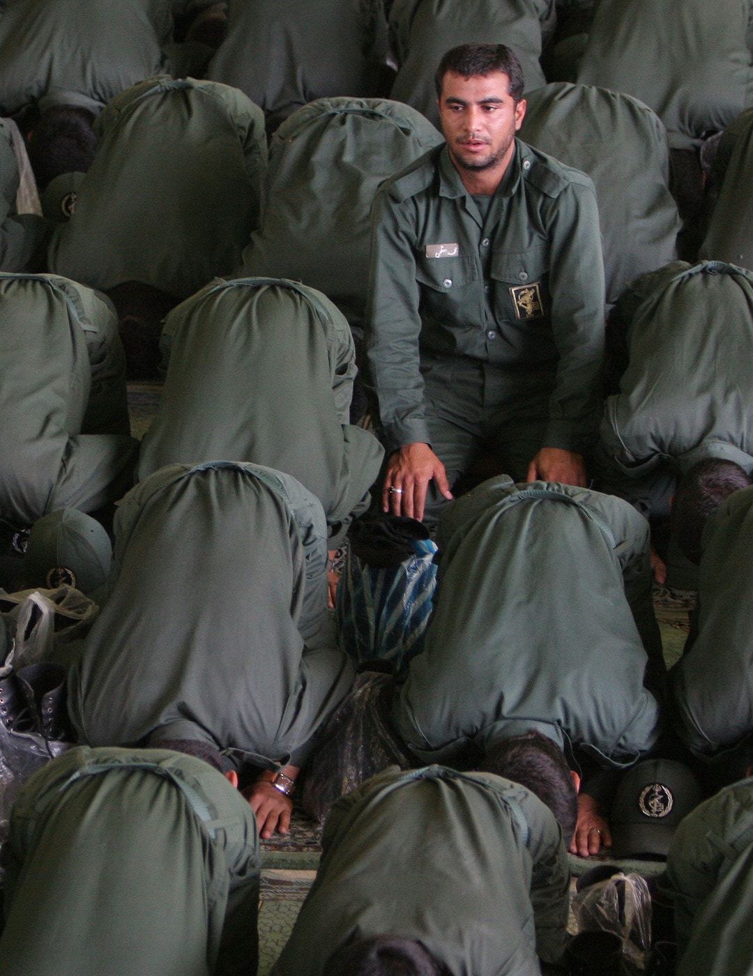 Militär man i uniform sitter bland människor som ber