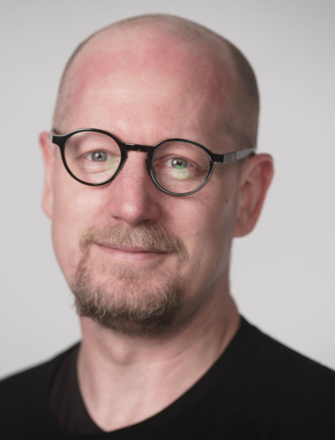 Porträttbild på Carl Heath i svart t-shirt och svarta glasögon.