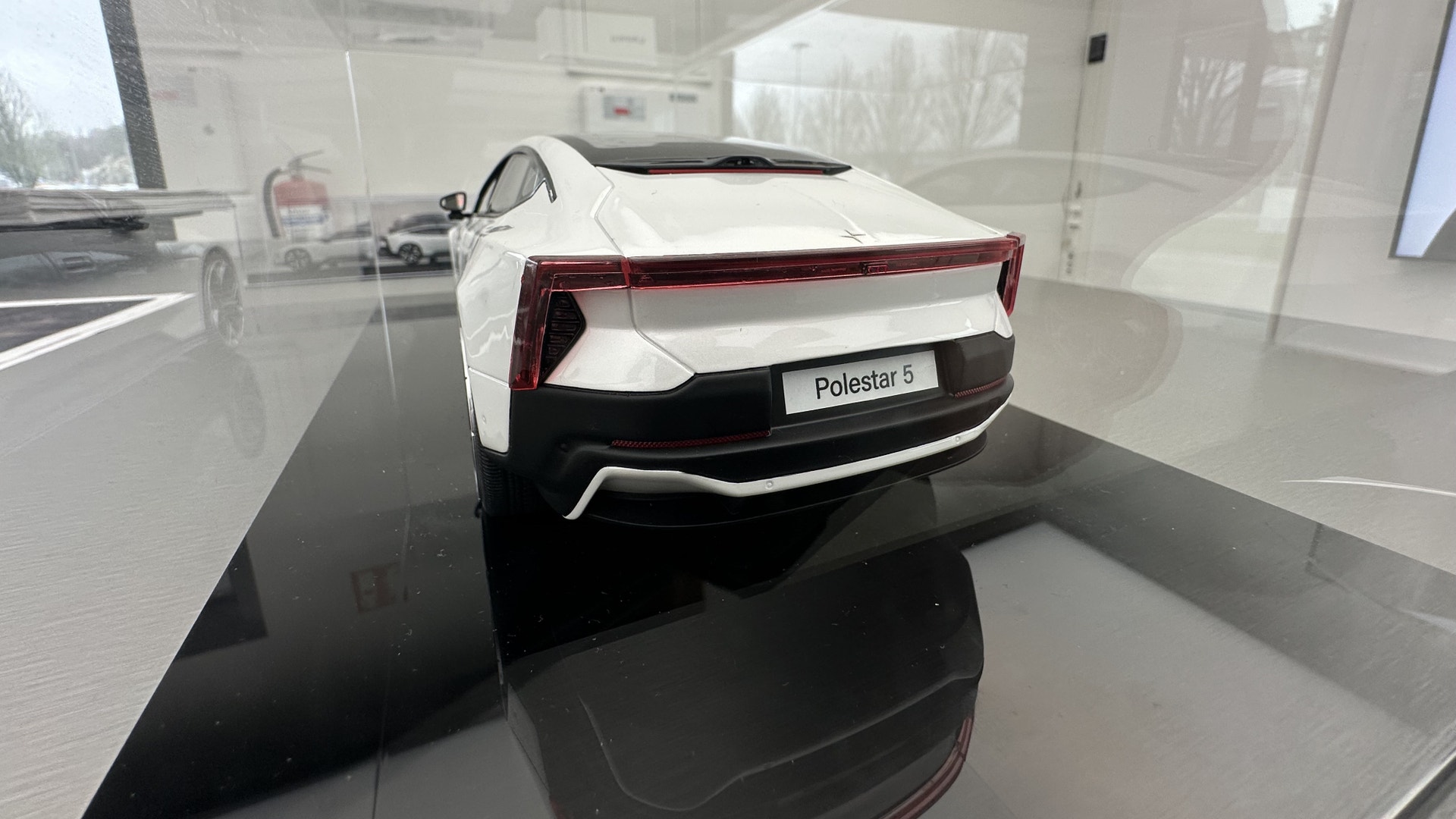En vit Polestar-bilmodell på en svart piedestal i ett utställningsrum.