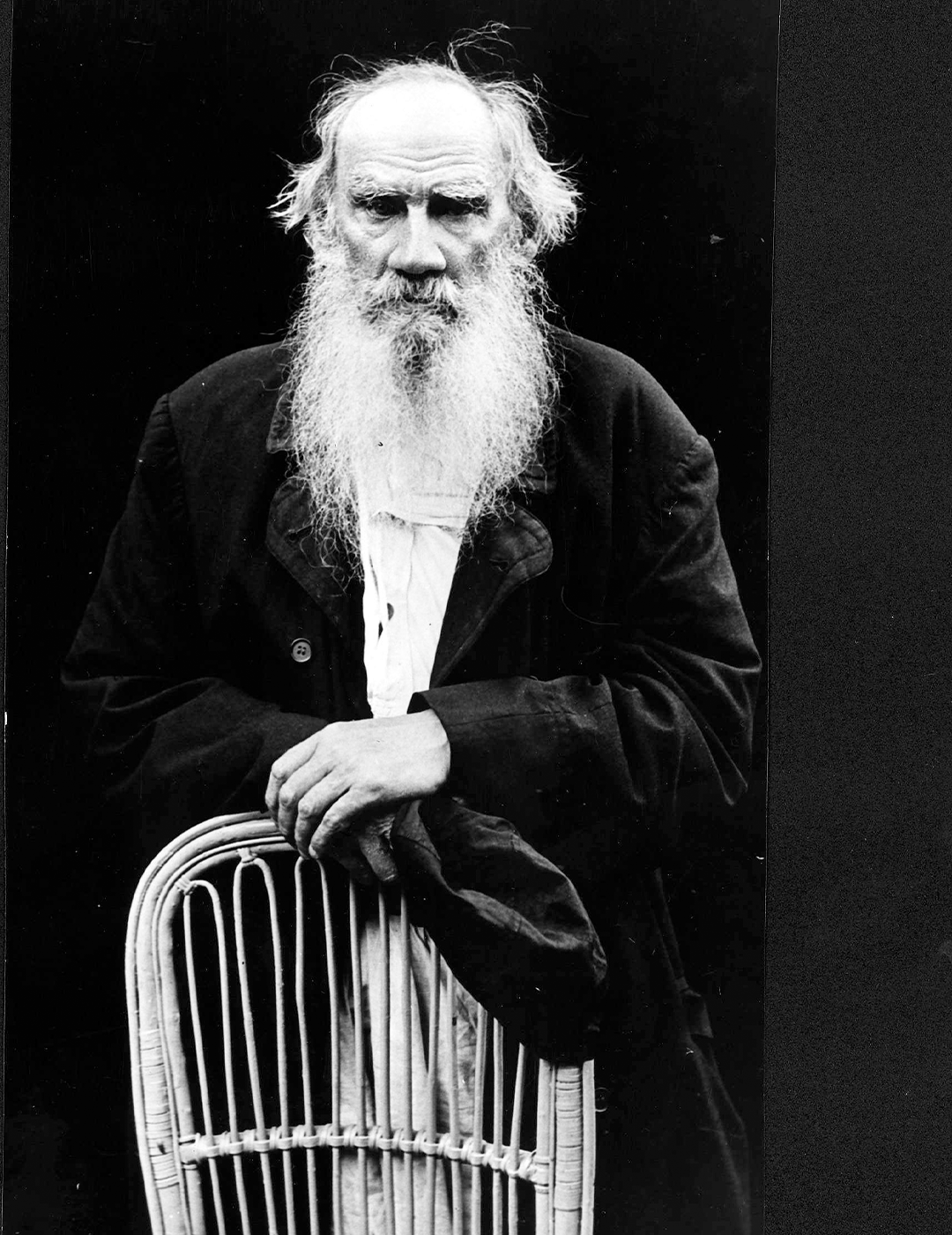 Svartvit porträttfotografi av en äldre man med långt skägg, iklädd mörk formell klädsel.