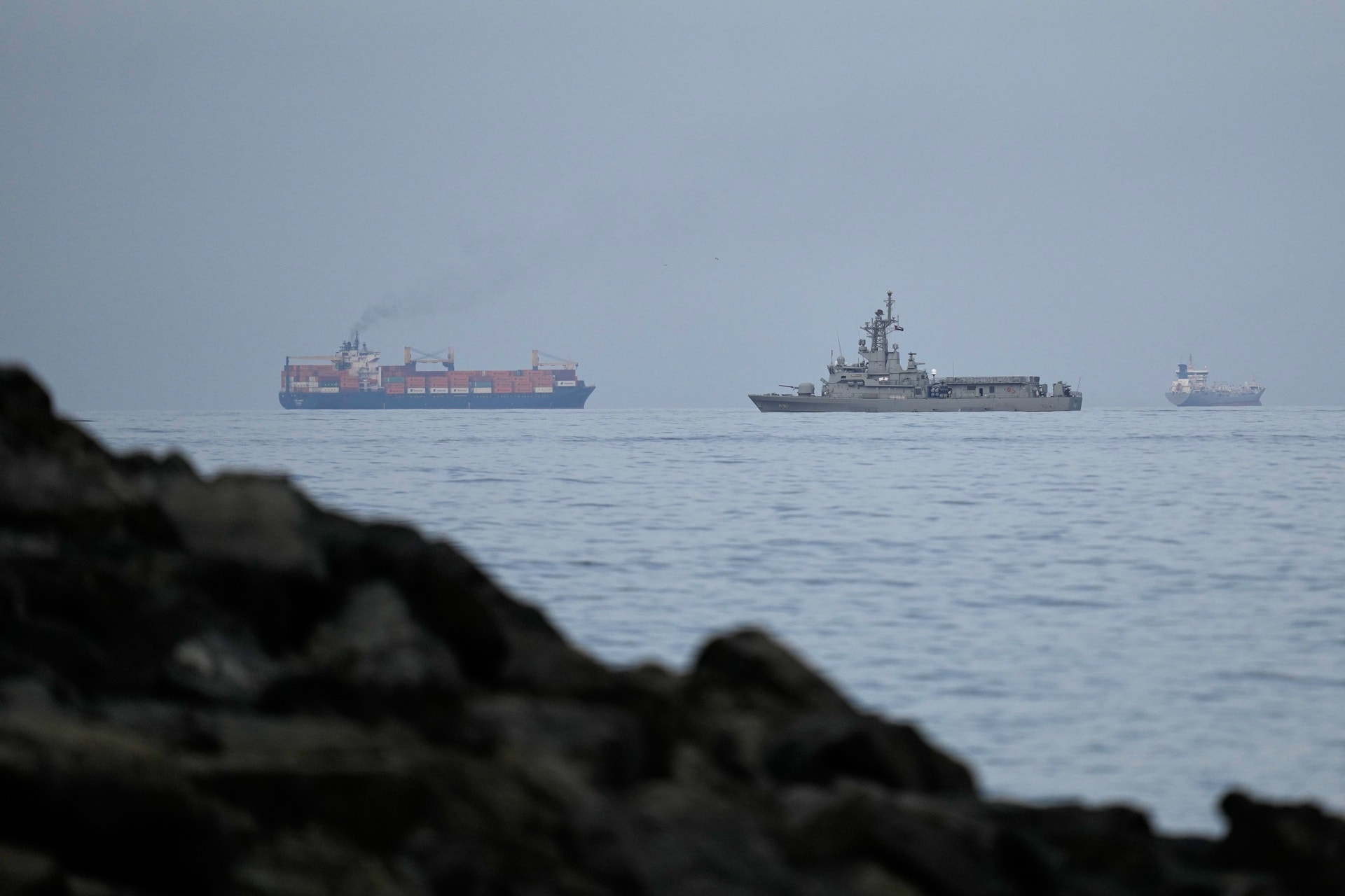 En marinbåt från Förenade Arabemiraten följer ett lastfartyg genom Hormuzsundet.
