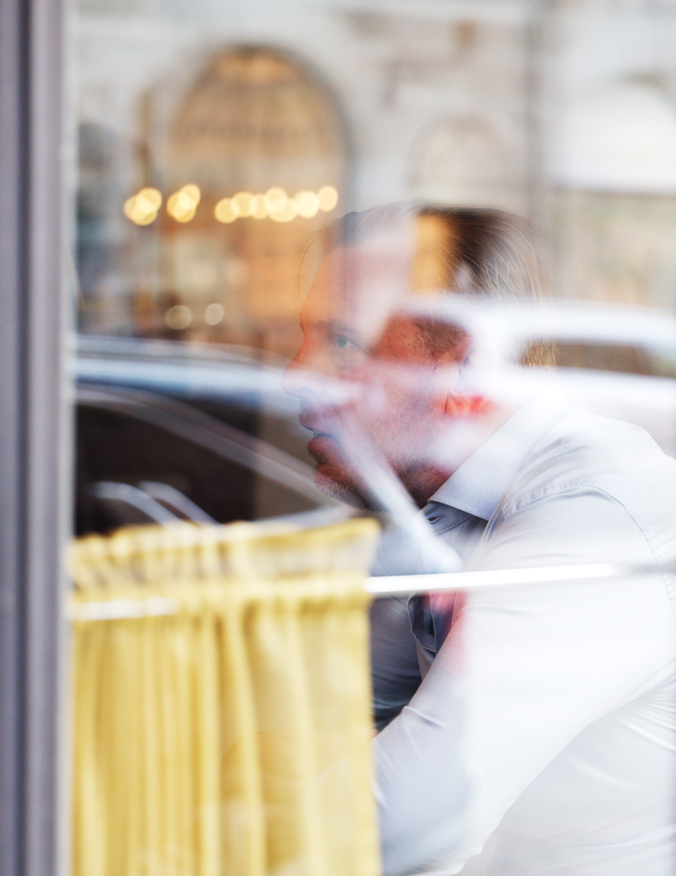 Person tittar ut genom ett fönster med gul gardin