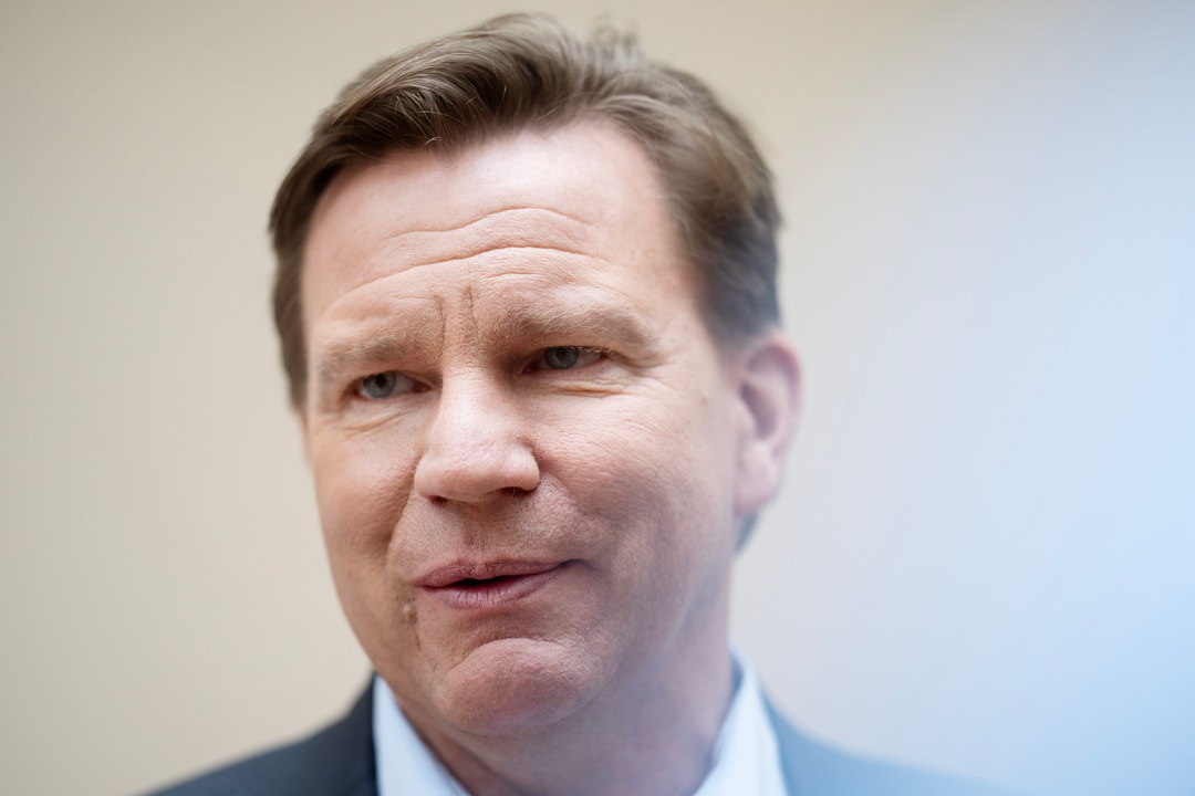 Porträtt av en man i kostym mot neutral bakgrund