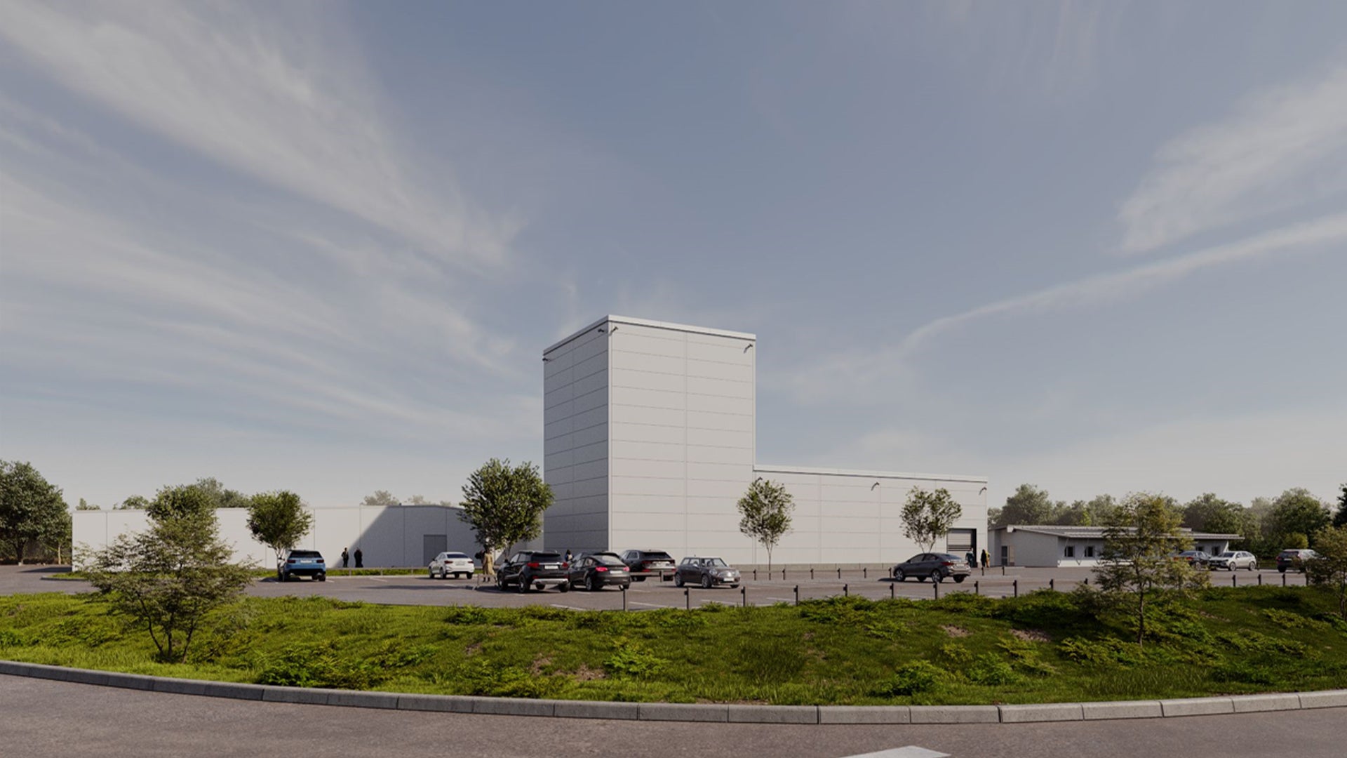 Modern industribyggnad med vita och grå fasader, omgiven av parkerade bilar och gröna växter.
