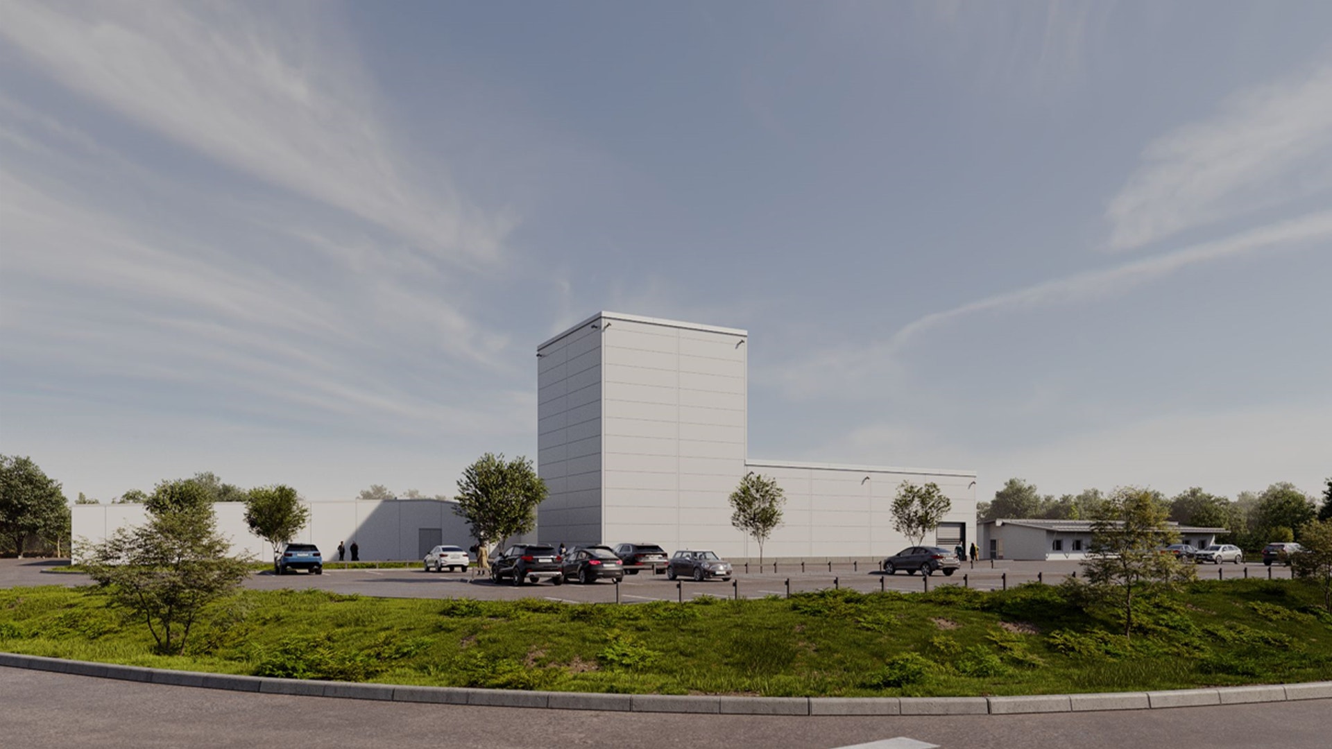Modern industribyggnad med vita och grå fasader, omgiven av parkerade bilar och gröna växter.