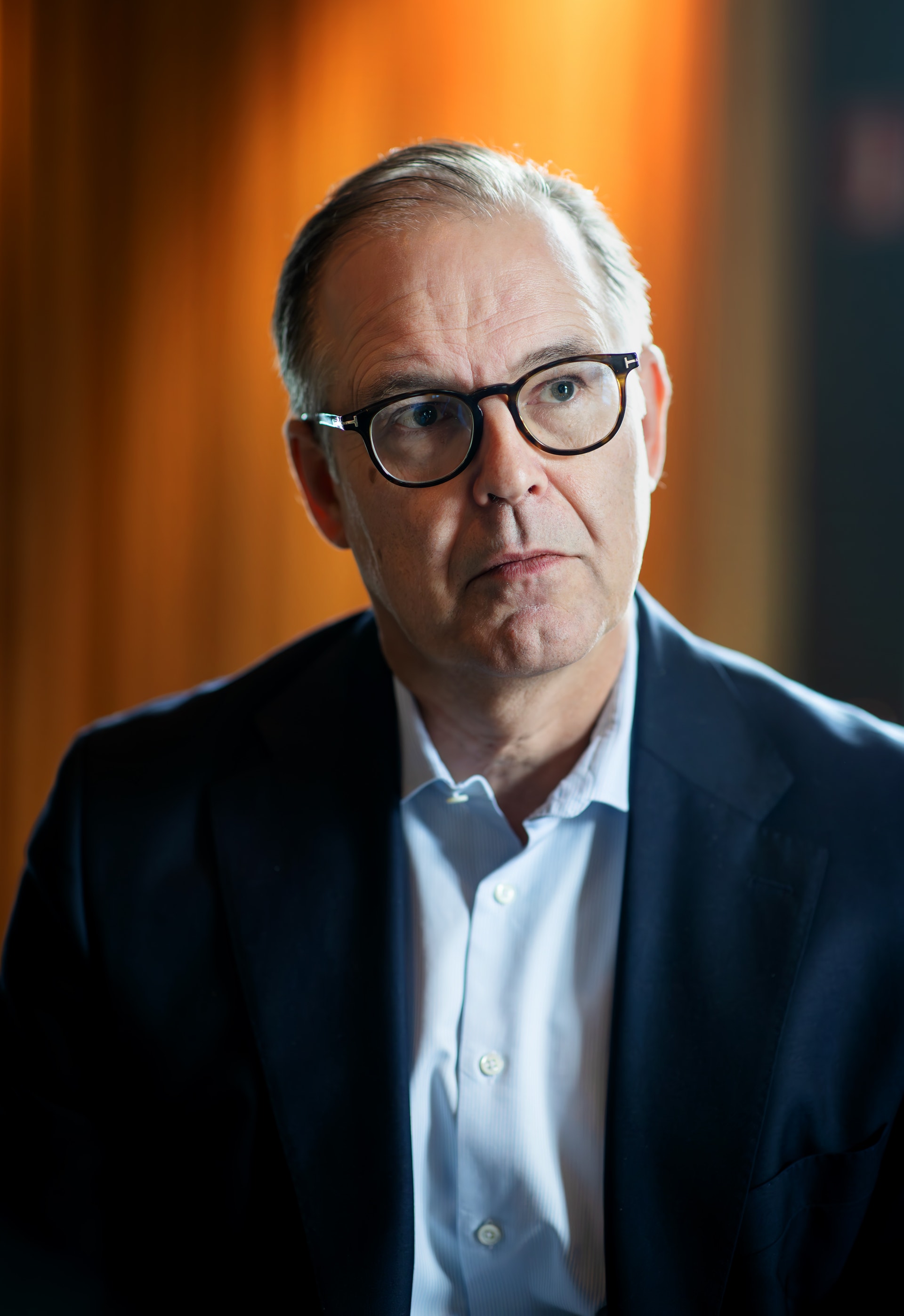 Porträttfoto Anders Borg med grått hår och glasögon, iklädd mörkblå kavaj och ljusblå skjorta.