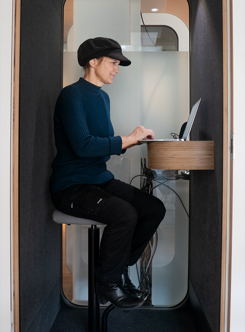 Stina Ehrensvärd sitter och arbetar i en liten telefonbox.