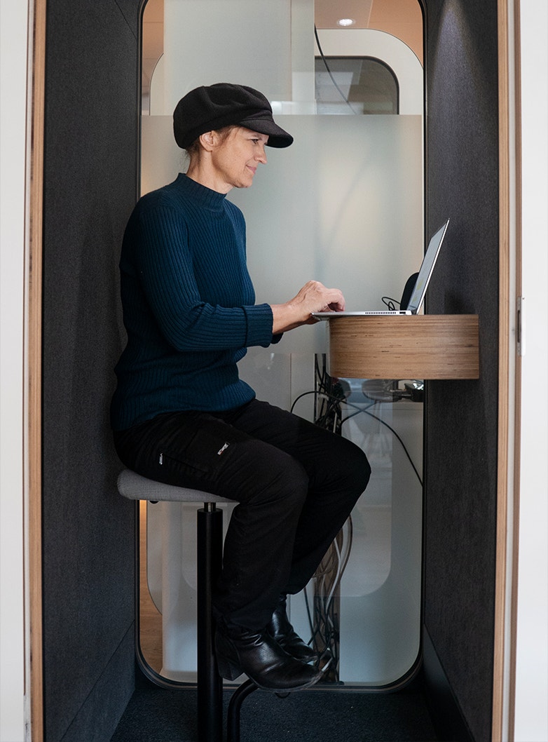 Stina Ehrensvärd sitter och arbetar i en liten telefonbox. 