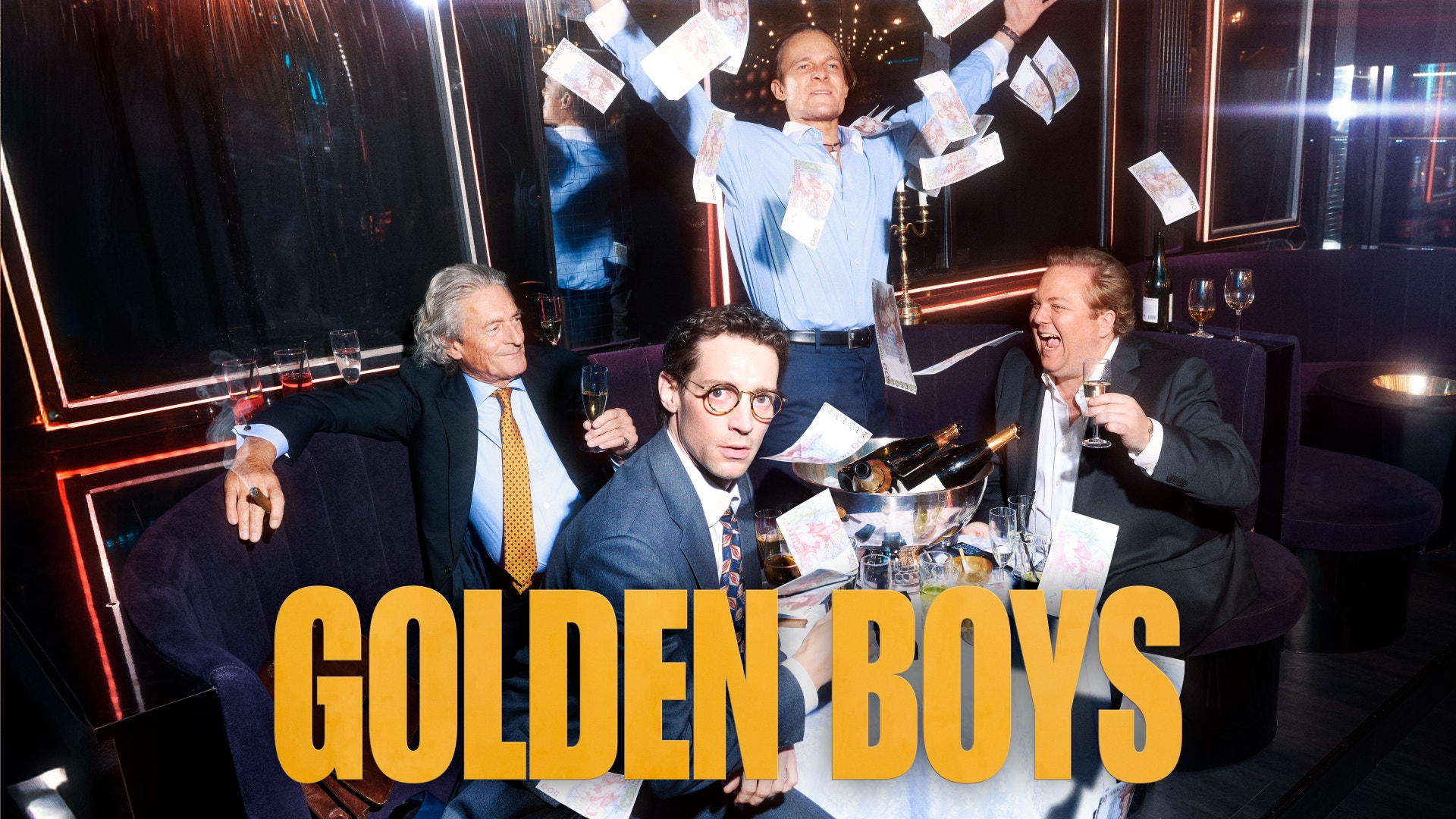 Promobild från TV-serien Golden Boys. Fyra män i en elegant miljö med neonbelysning. En man står i mitten med armarna höjda och kastar pengar i luften, medan tre andra män sitter vid ett bord omkring honom.