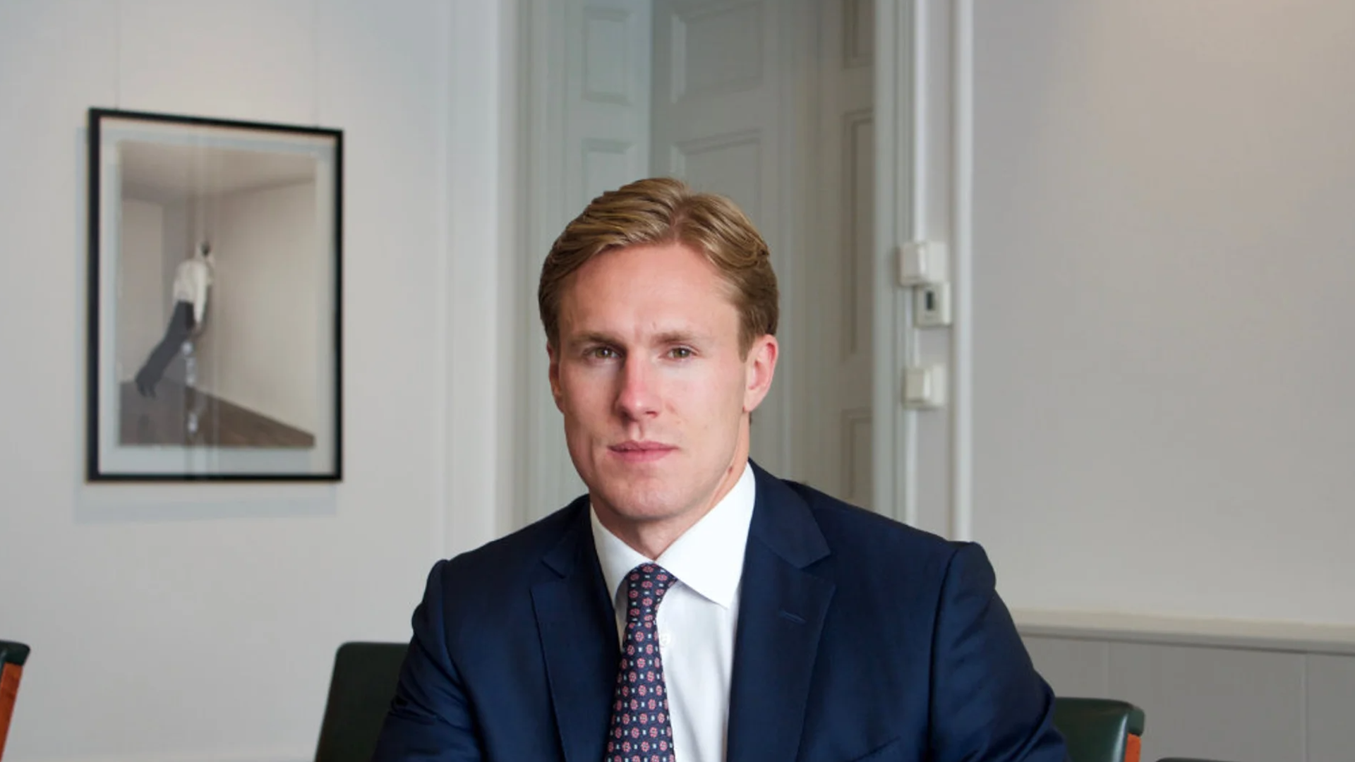Porträtt av Alexander Jansson, vd för CB Fonder, sittande i mörk kostym och slips i ett kontorsrum.