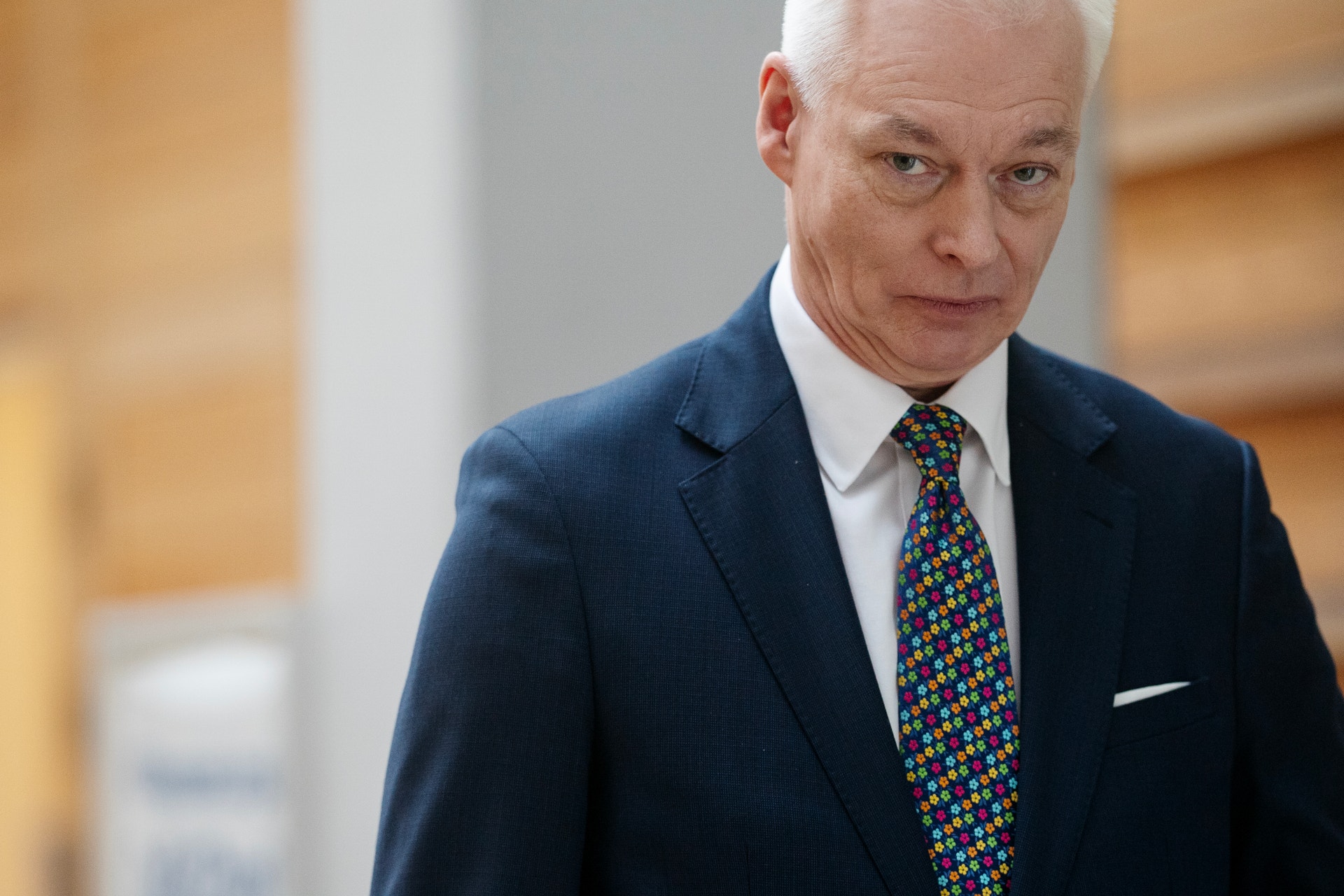 Äldre man i mörkblå kostym och färgglad slips